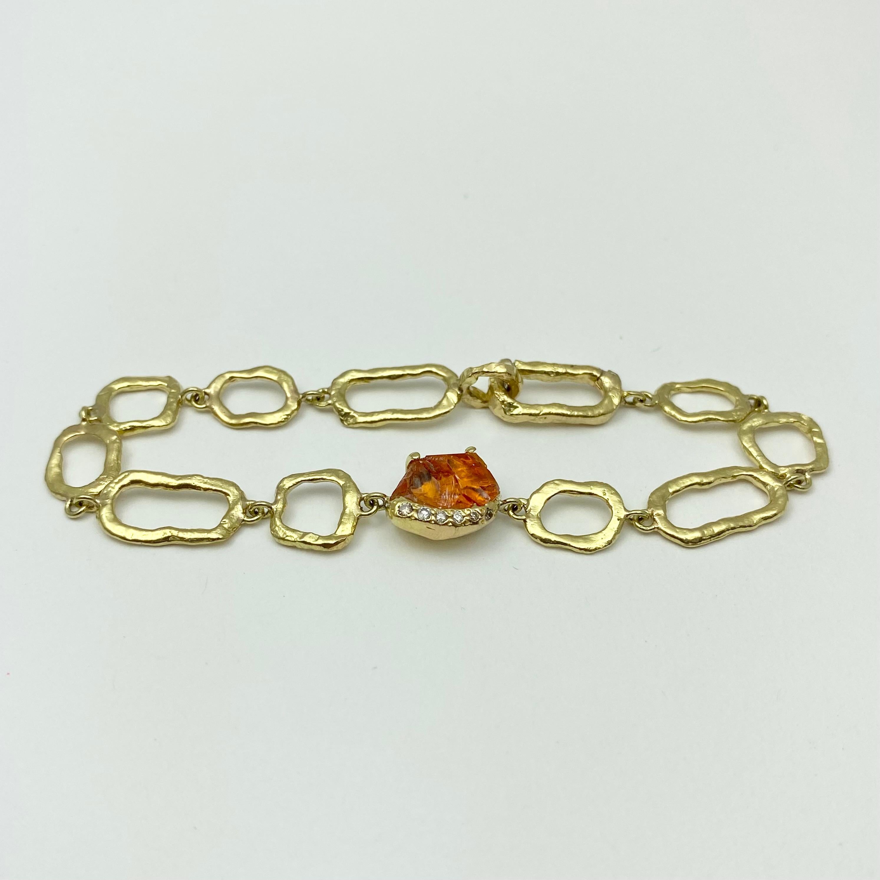 The Gladwell on Links bracelet is hand-crafted with 18-karat recycled yellow gold, and features one untreated, Tenda Cut, natural orange color spessartine garnet (also called spessartite); and six round champagne accent diamonds. The Gladwell
