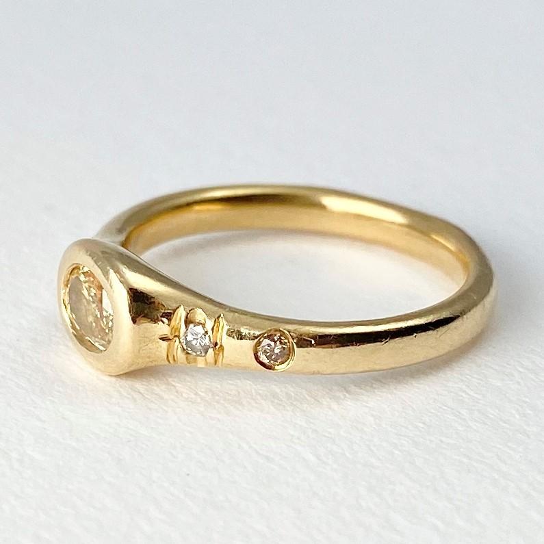 The Pebble pinky ring, from our Barefoot Collection, is hand-crafted in 18-karat recycled yellow gold. This Pebble ring features one bezel set, yellow color oval diamond; and three round, champagne accent diamonds. A petite signet style ring,