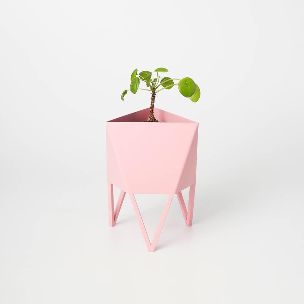 Introducing Force/Collide's signature planter in flat light pink. Using a seamless brake-forming technique, one sheet of steel is wrapped into a unique geometric pattern that's triangular at the top and hexagonal at the base. Three V-shaped legs