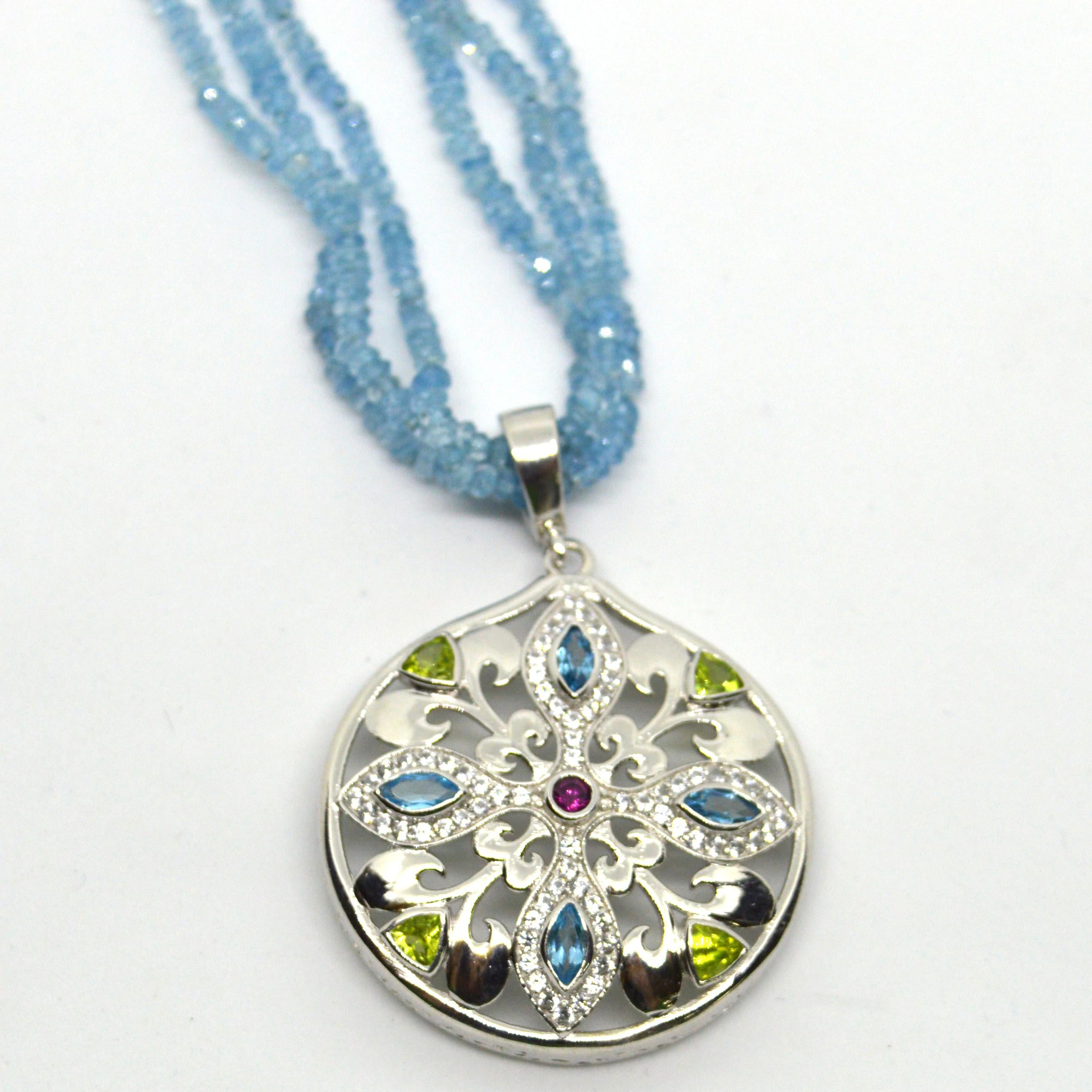 This delicate detachable pendant falls from 3 Strands of fine faceted Aquamarine hand knotted for strength and durability with a Sterling silver CZ clasp. The pendant is Rhodium plated Sterling Silver set with Peridot Trillions, Marquise Blue Topaz