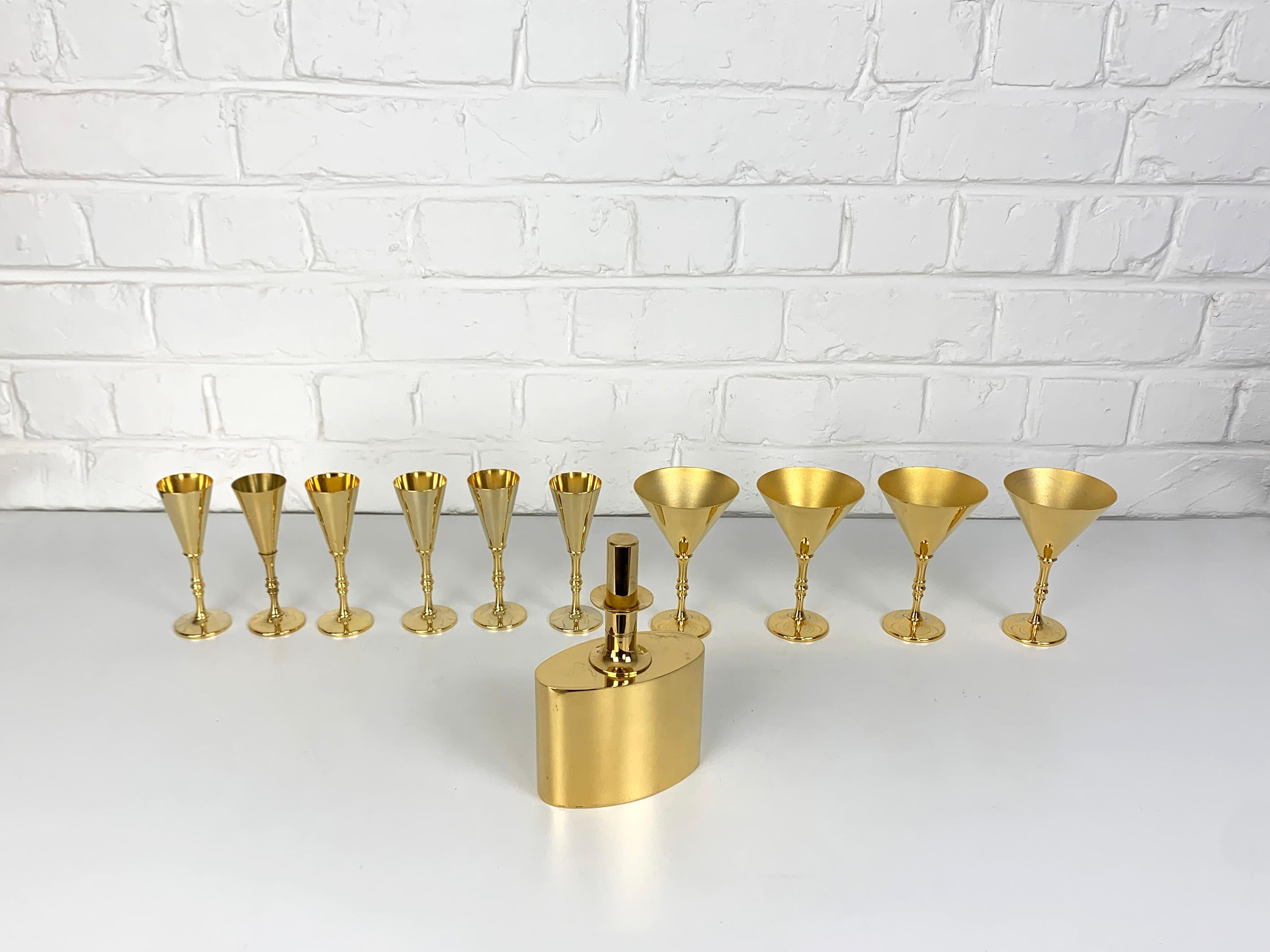 Elegant Decanter and 10 Shot Glasses made from brass. Gold plated, 23 Carat.

Designed by Pierre Forssell and manufactured in Sweden by Skultuna. The company was founded by King Carl IX of Sweden in 1607. Pierre Forsell worked between 1955 and 1986