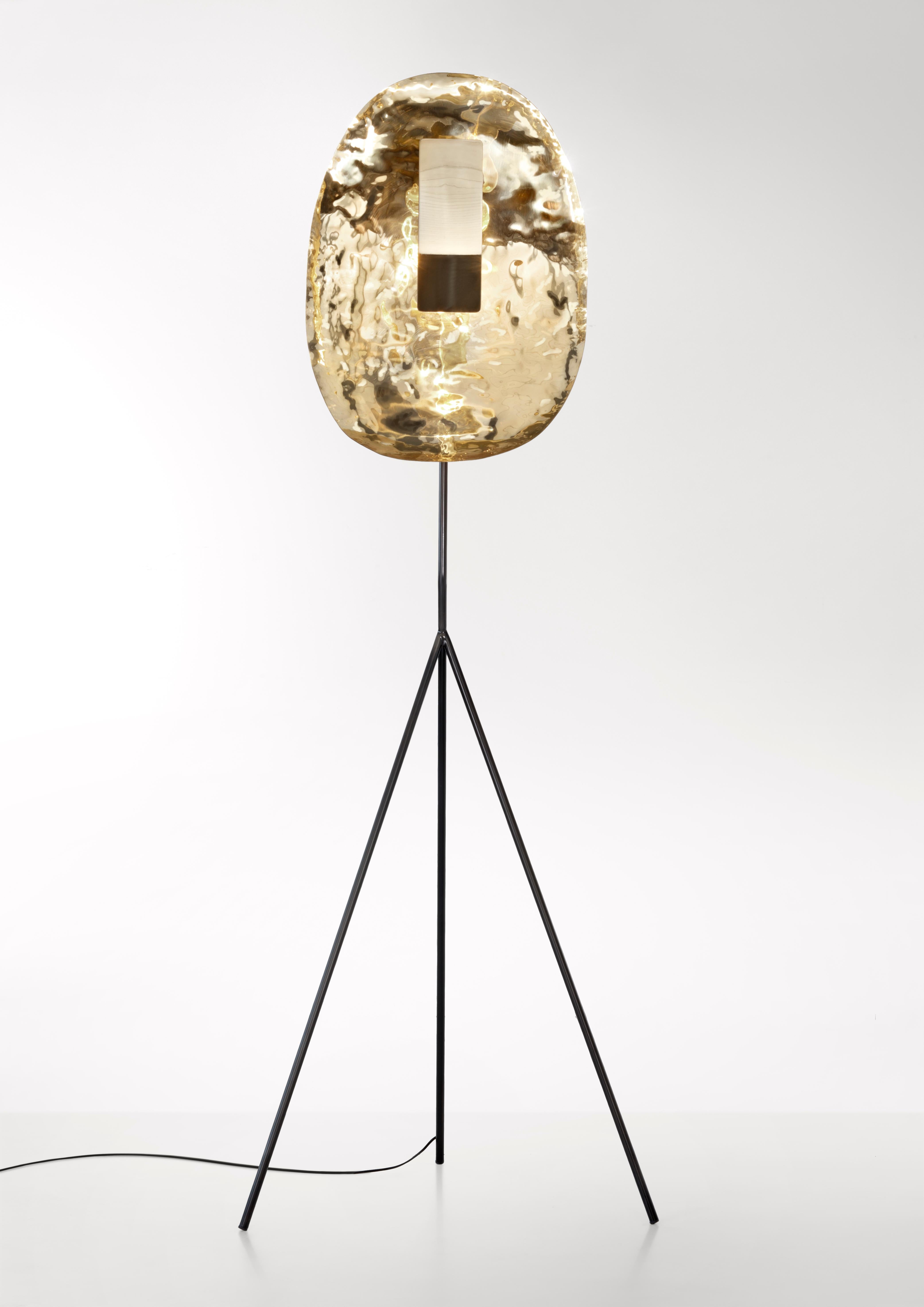 A flowing, sensible presence, delicately balanced. A sculptural object composed of a hand-hammered brass diffuser, metal that still seems to radiate the energy of the tool that shaped it. Light, originating from a LED source, is reflected as if it