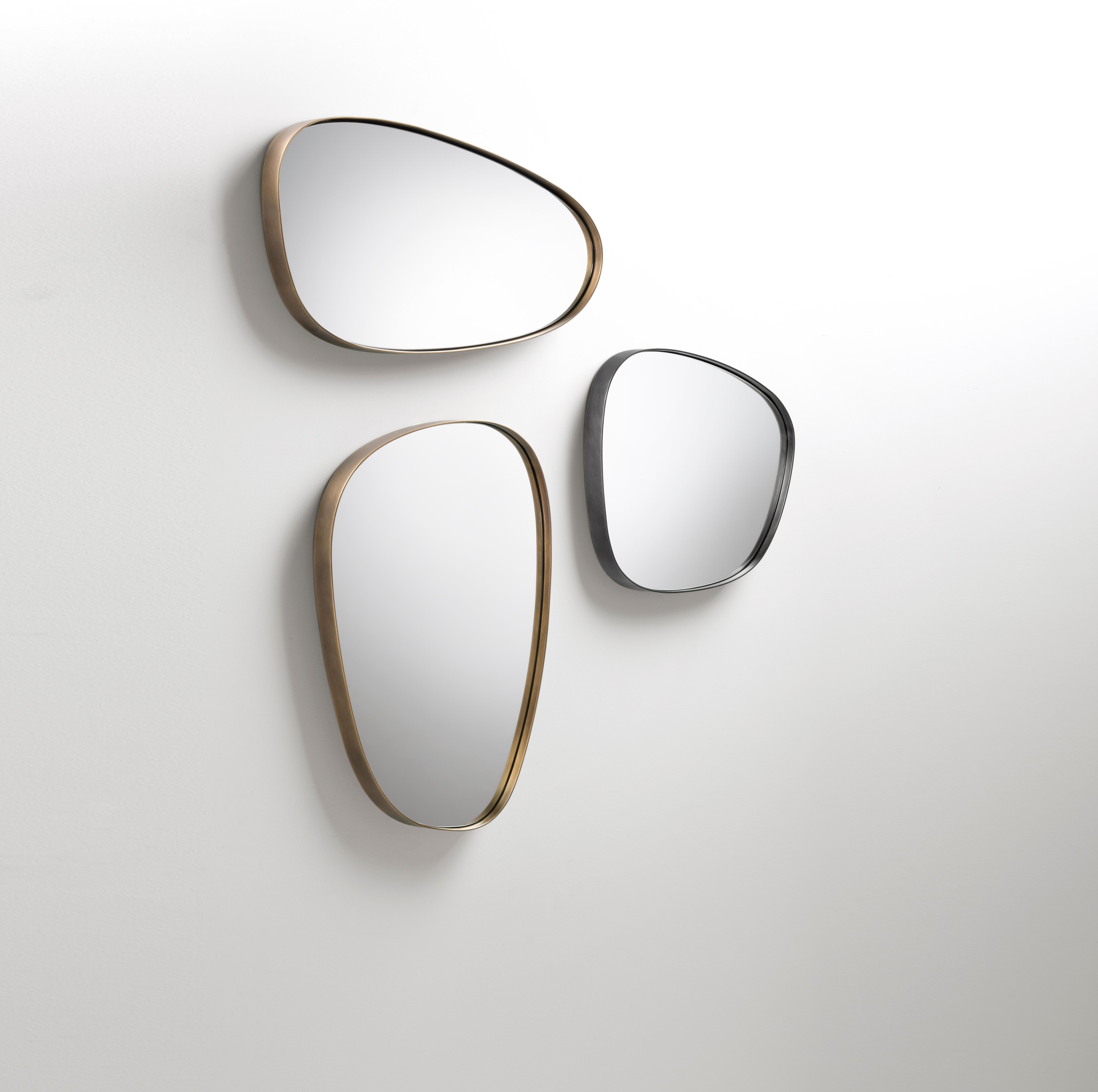 Syro Mirror echoes the organic silhouettes of the entire Syro collection, translating them into mirrored surfaces that, surrounded by thick iron and brass frames, mimic the natural outlines of petals. In a mix of chromatic effects obtained from