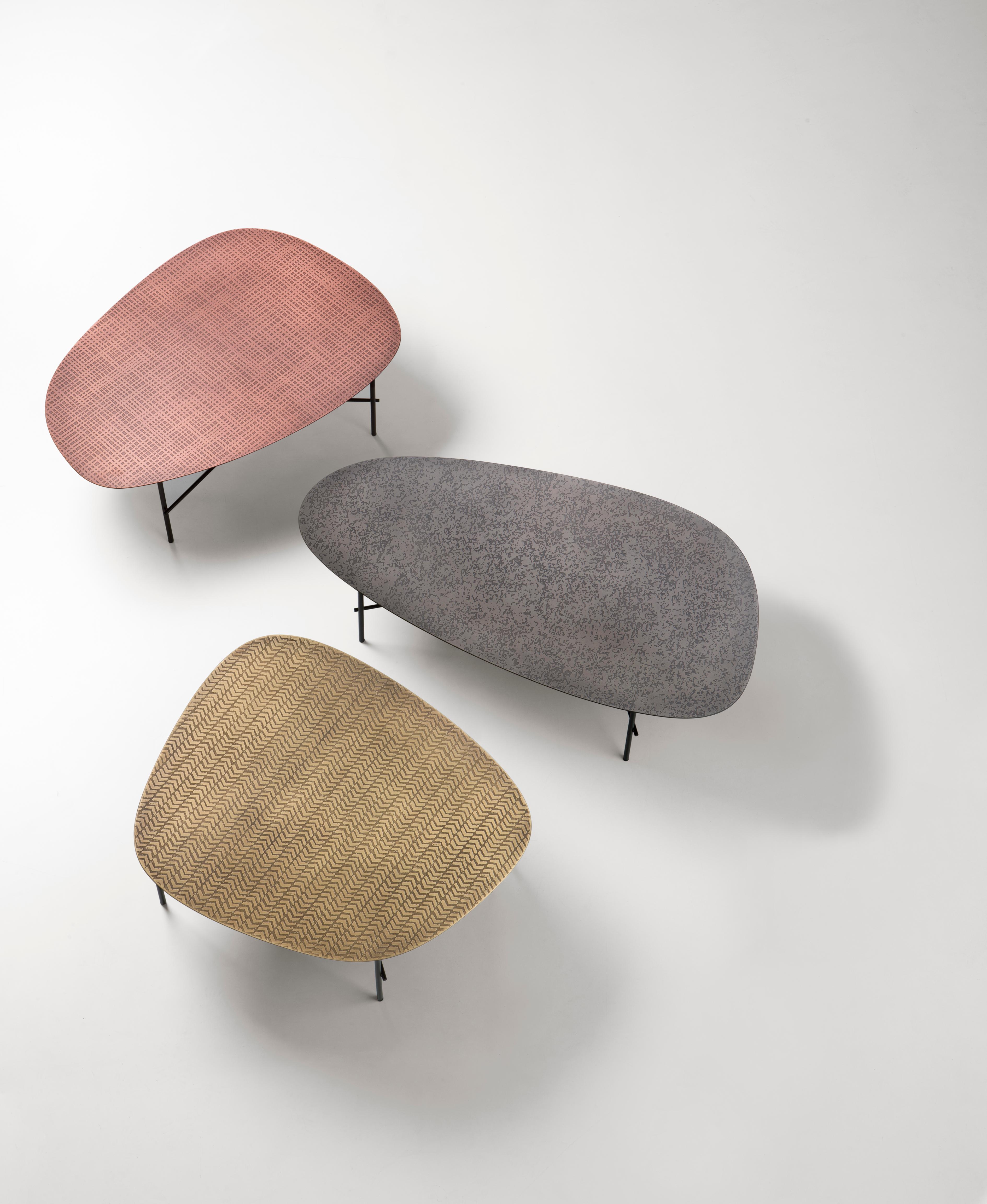 Version surdimensionnée des tables d'appoint Syro, Syro XL est caractérisée par la finition DeErosion qui définit le plateau. De profondes érosions dans le métal créent des paysages le long des proportions généreuses de la forme, mettant en valeur