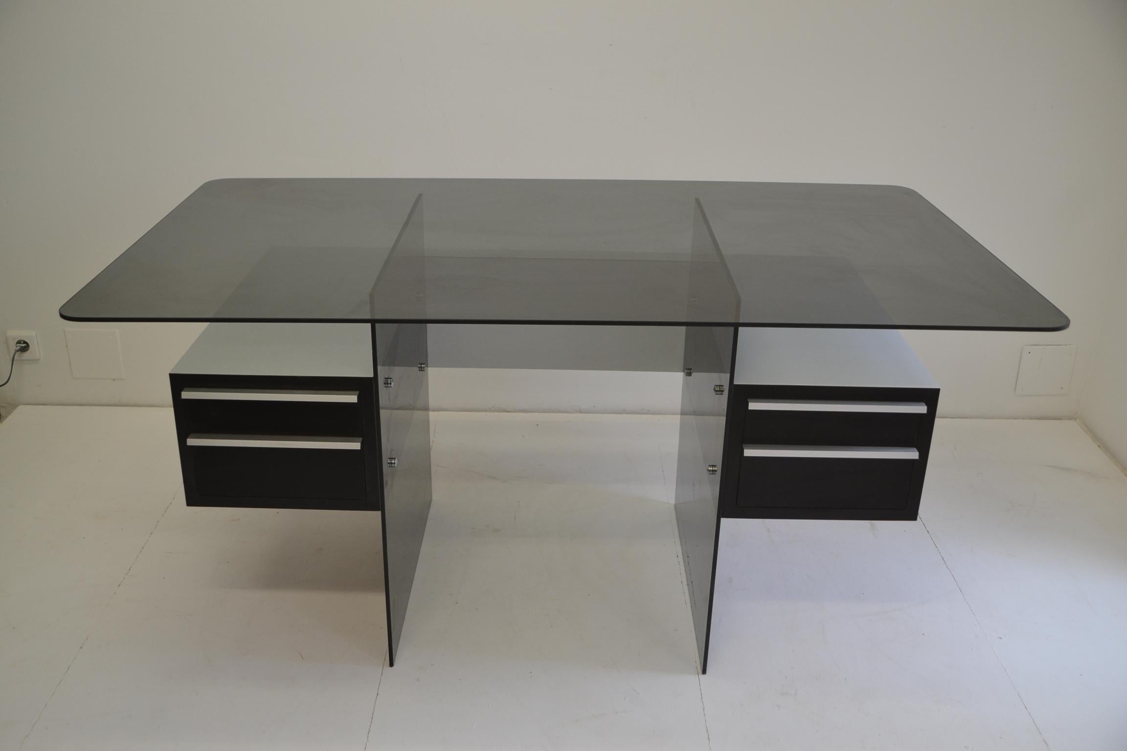 Xavier MARBEAU Office made of glass, steel and wood from the 1970s. Frame in glass and frame with 2 wooden storage boxes on each side. Spacer in glass and top plate in smoked glass. The storage boxes are composed of 2 drawers in black oak veneer. In