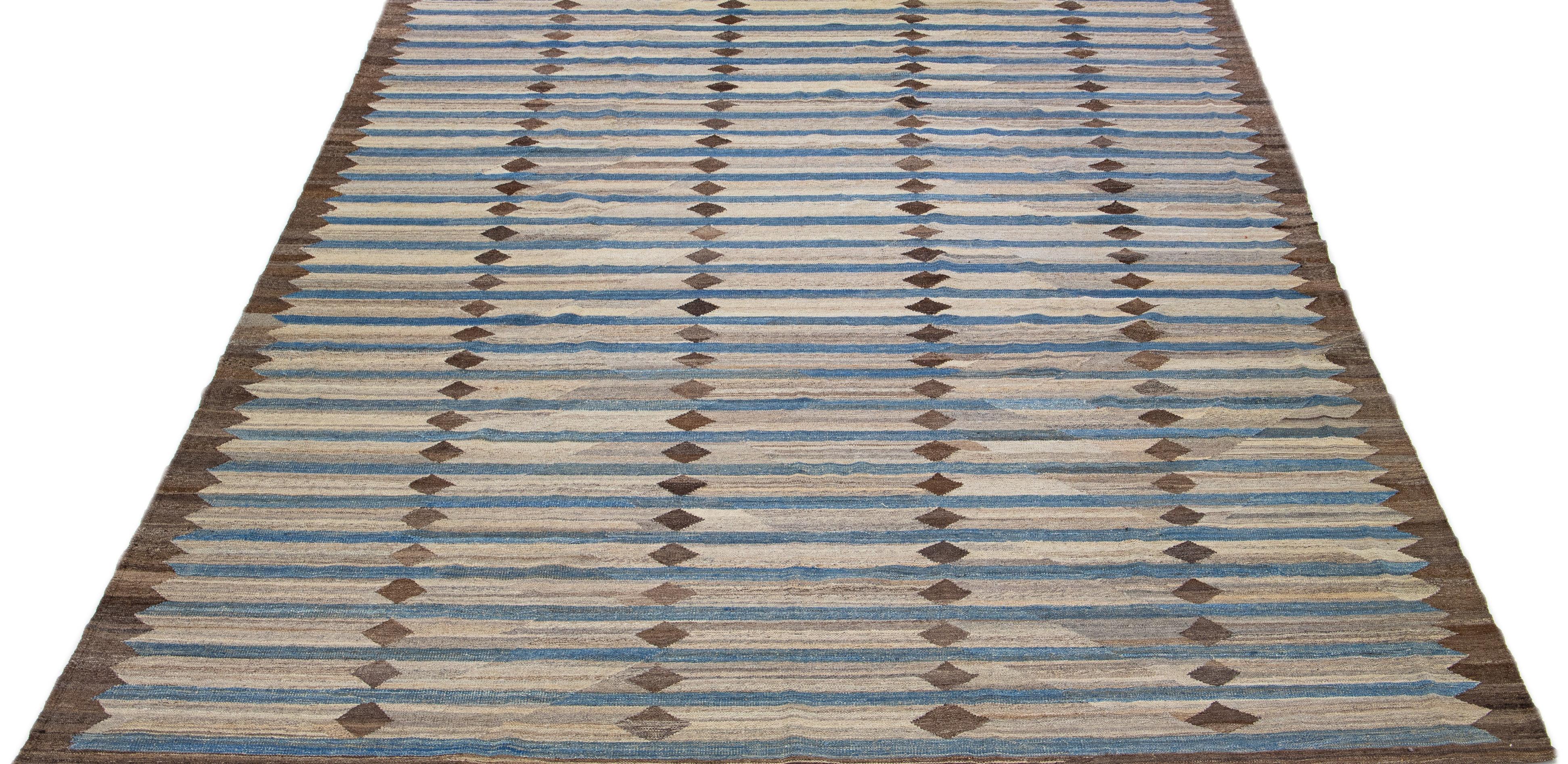 This Deco flatweave wool rug exhibits a fascinating brown color field with blue accents, creating a contemporary and aesthetically-pleasing Geometric design. This classic design motif can be incorporated into any room, providing a stylish and