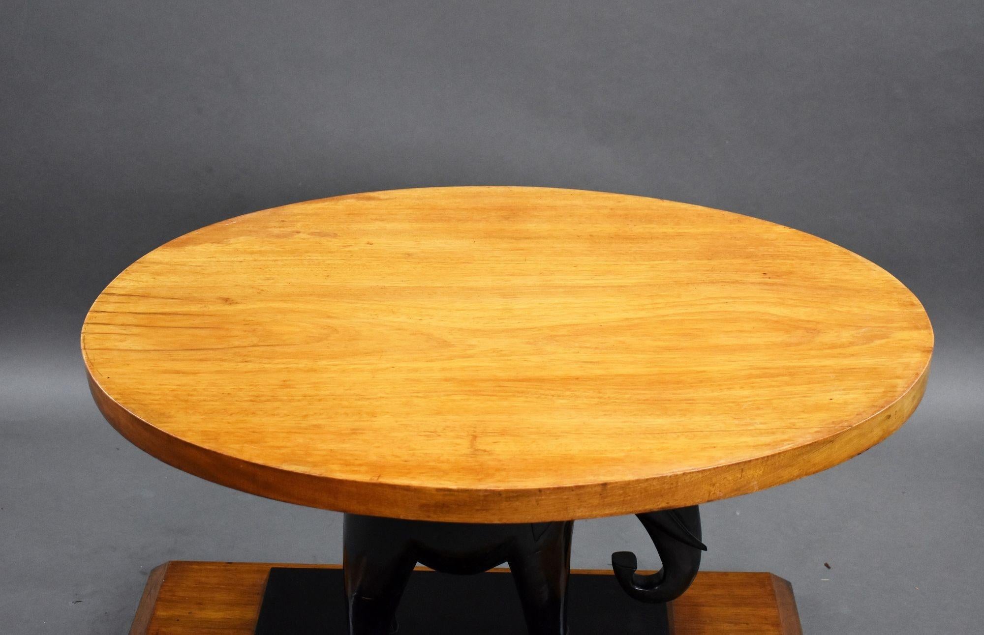 Table basse déco en noyer et éléphant d'ébène en bon état avec plateau ovale reposant sur un éléphant d'ébène sur une base en noyer. La table a un plateau en verre pour la protéger.