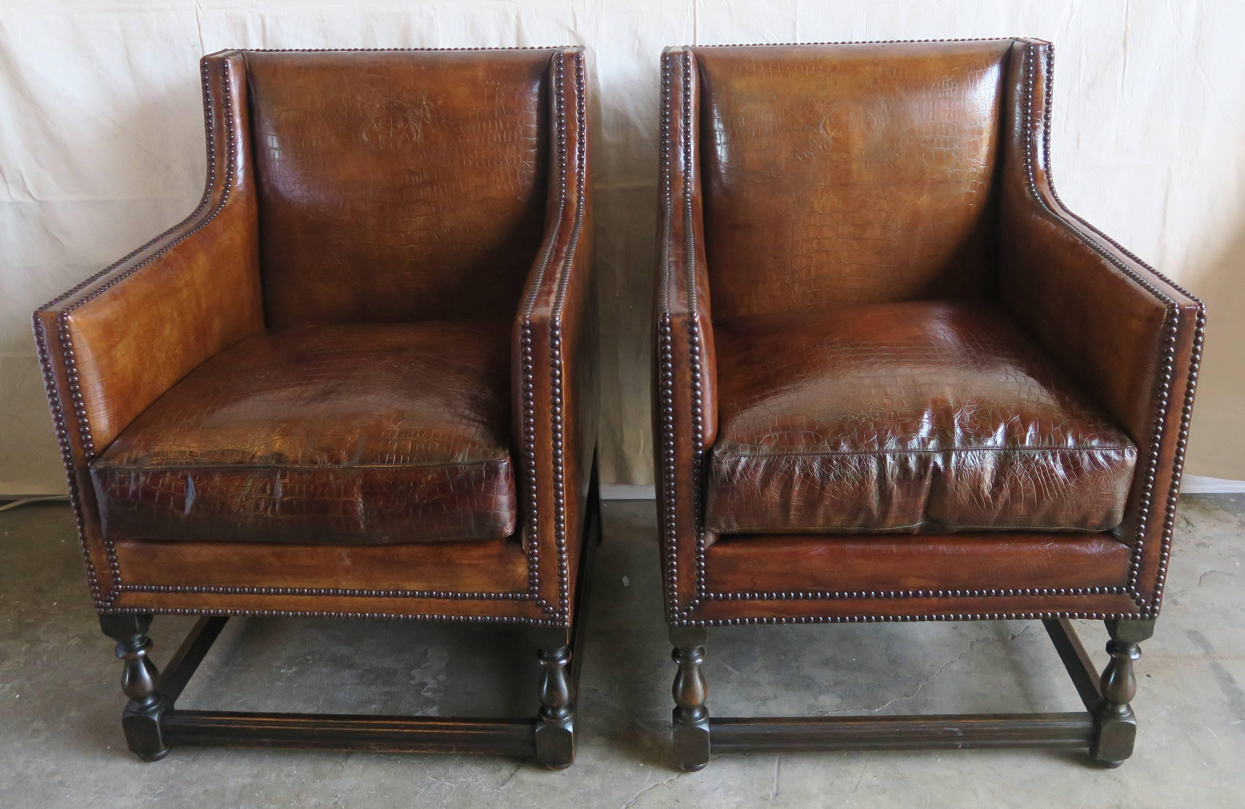 Pair of 1930s Deco style club chairs upholstered in a faux crocodile embossed leather with antique brass colored nailhead trim detail. Loose down filled cushions.
Measures: Seat height 20