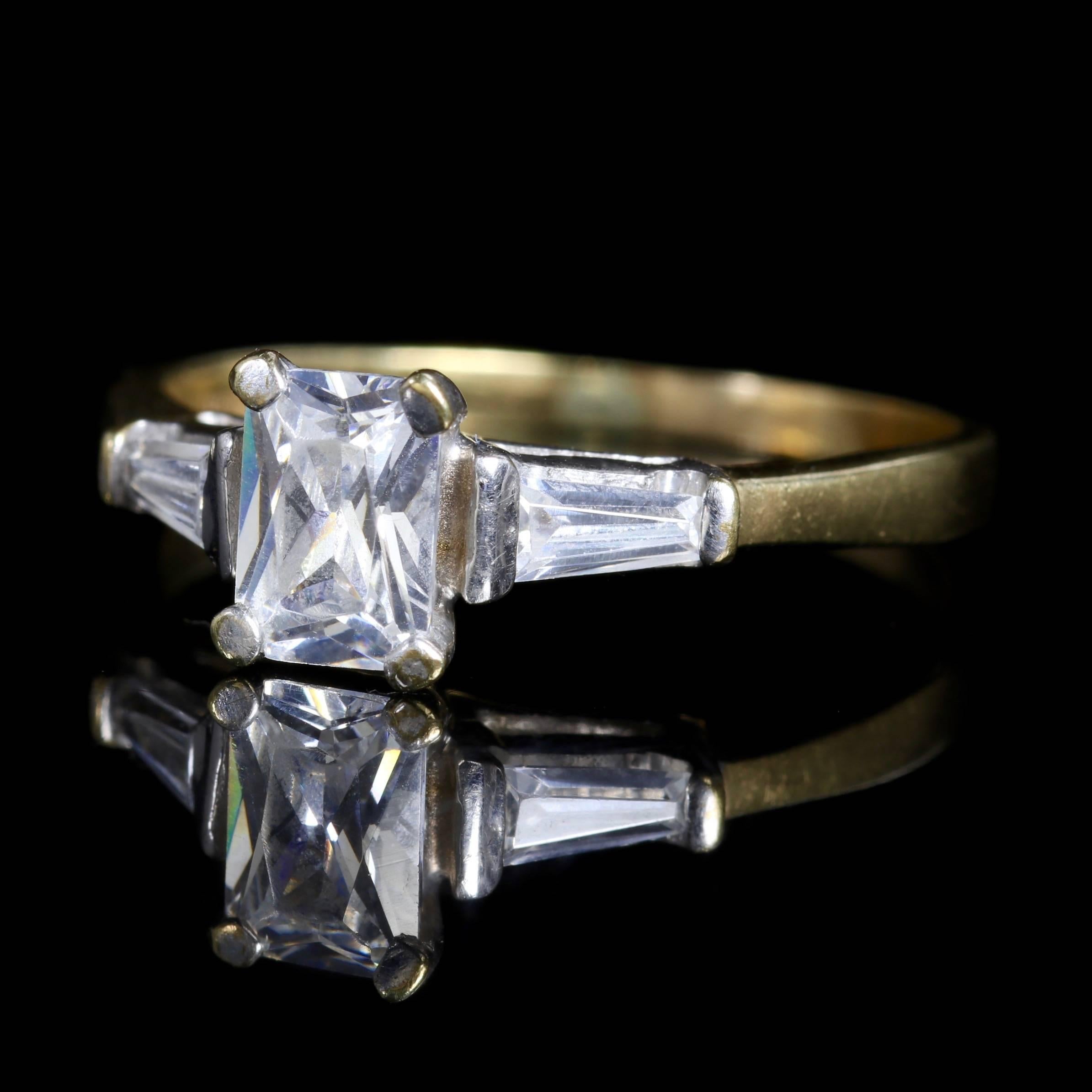 This Art Deco 9ct Yellow Gold and 9ct White Gold ring boasts a superb emerald cut Paste Stone.

The central stone is approx. 1.35ct baguette cut Paste Stones that chase down each shoulder.

Paste is hand-cut glass that has been polished with metal