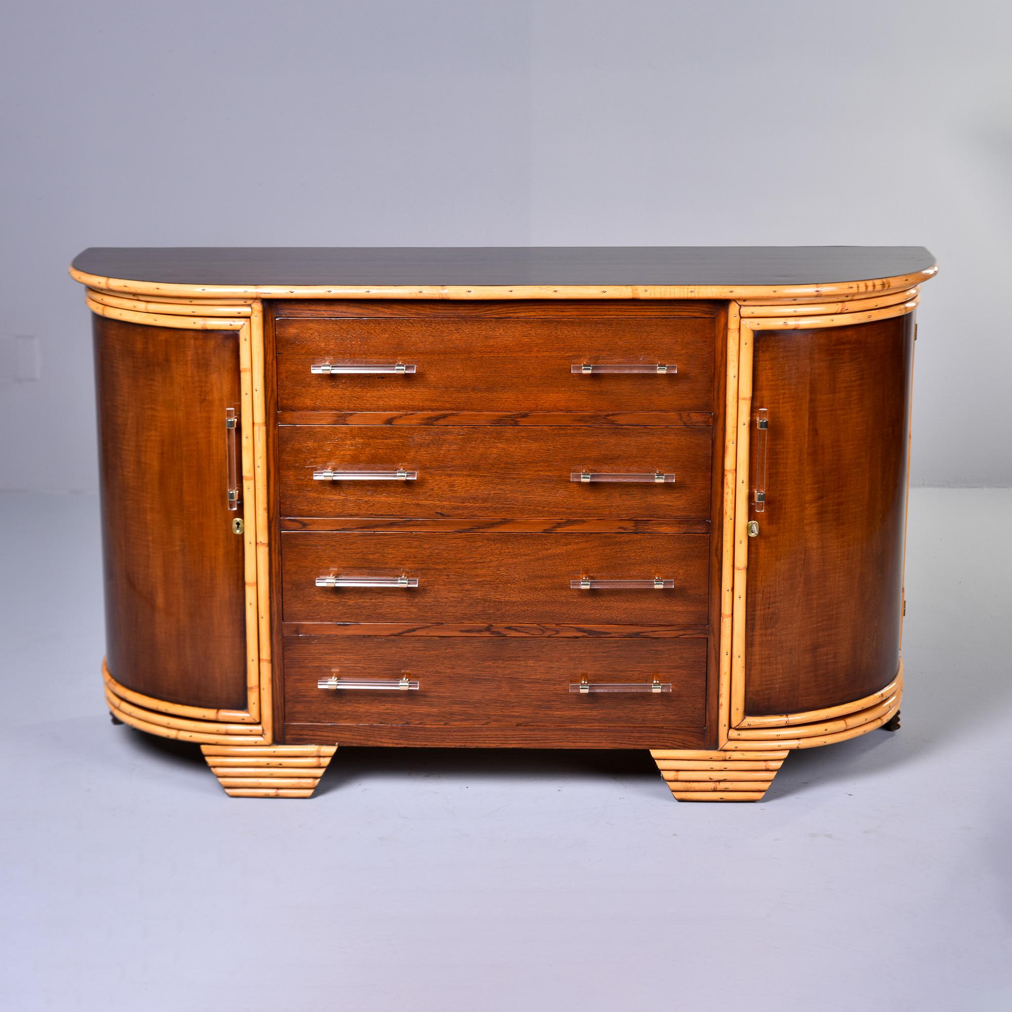 Found in France, this bow front cabinet dates from the 1940s. This appears to be made of walnut, but we can’t be sure, and has contrasting trim in blond bamboo. Cabinet features include four functional center drawers flanked by locking corner