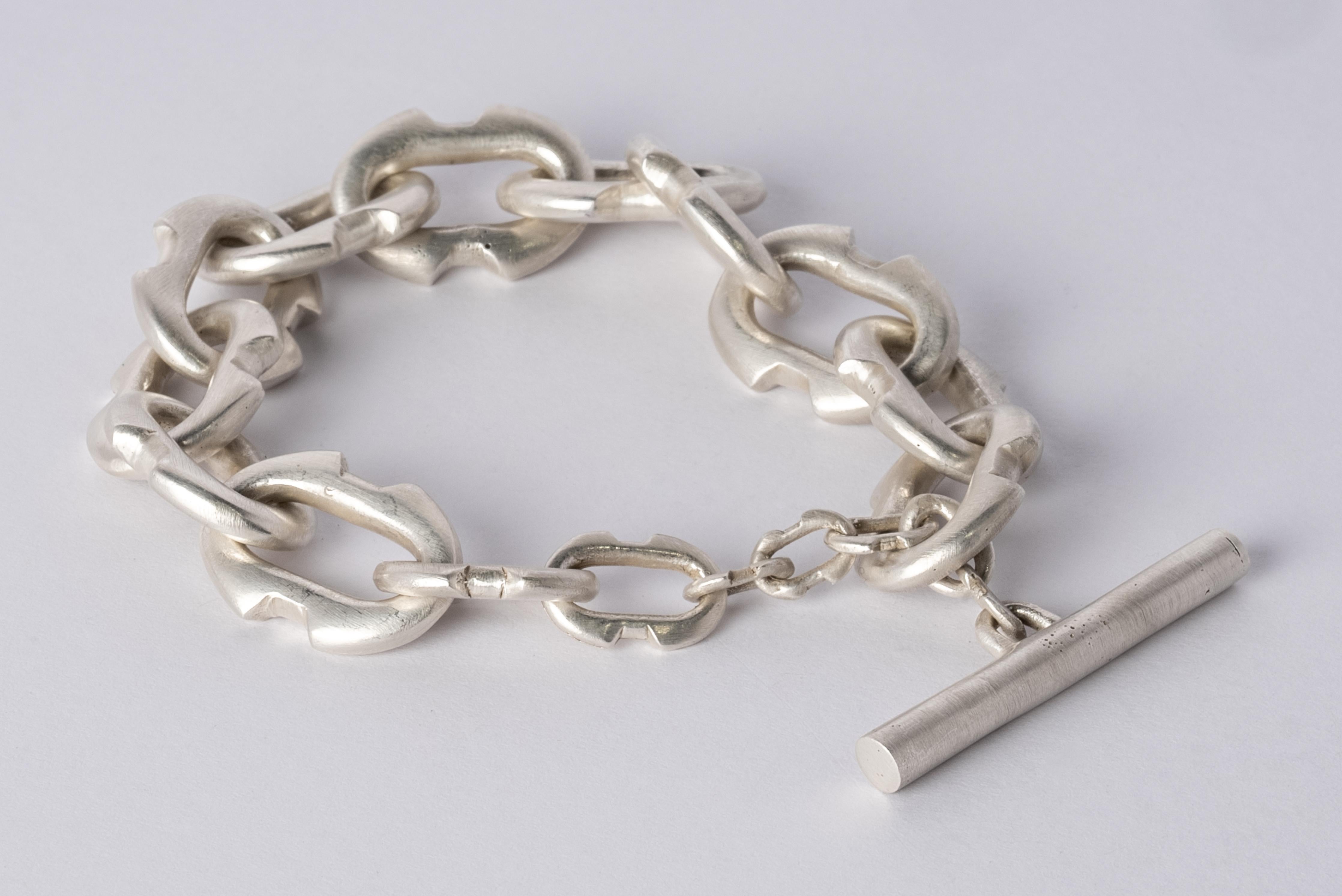 Bracelet in acid treated silver plated brass. This piece is 100% hand fabricated from metal plate; cut into sections and soldered together to make the hollow three dimensional form.
Dimensions:
Chain link size (L × H): 25 mm × 17 mm
Toggle length: