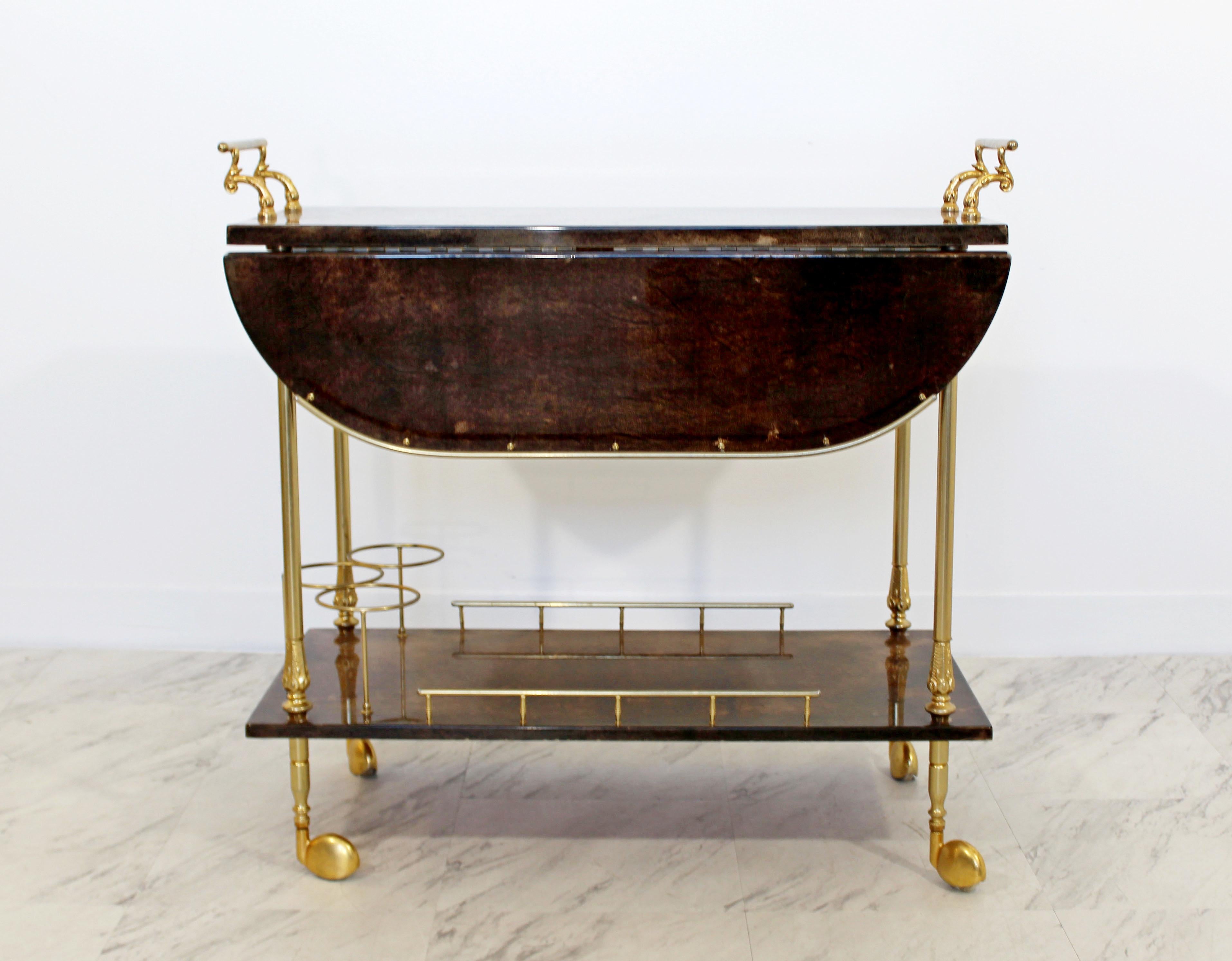 For your consideration is an absolutely stunning, brown goatskin lacquered bar cart, with brass accents, circa the 1950s. In very good condition. The dimensions with the leaves down are 31
