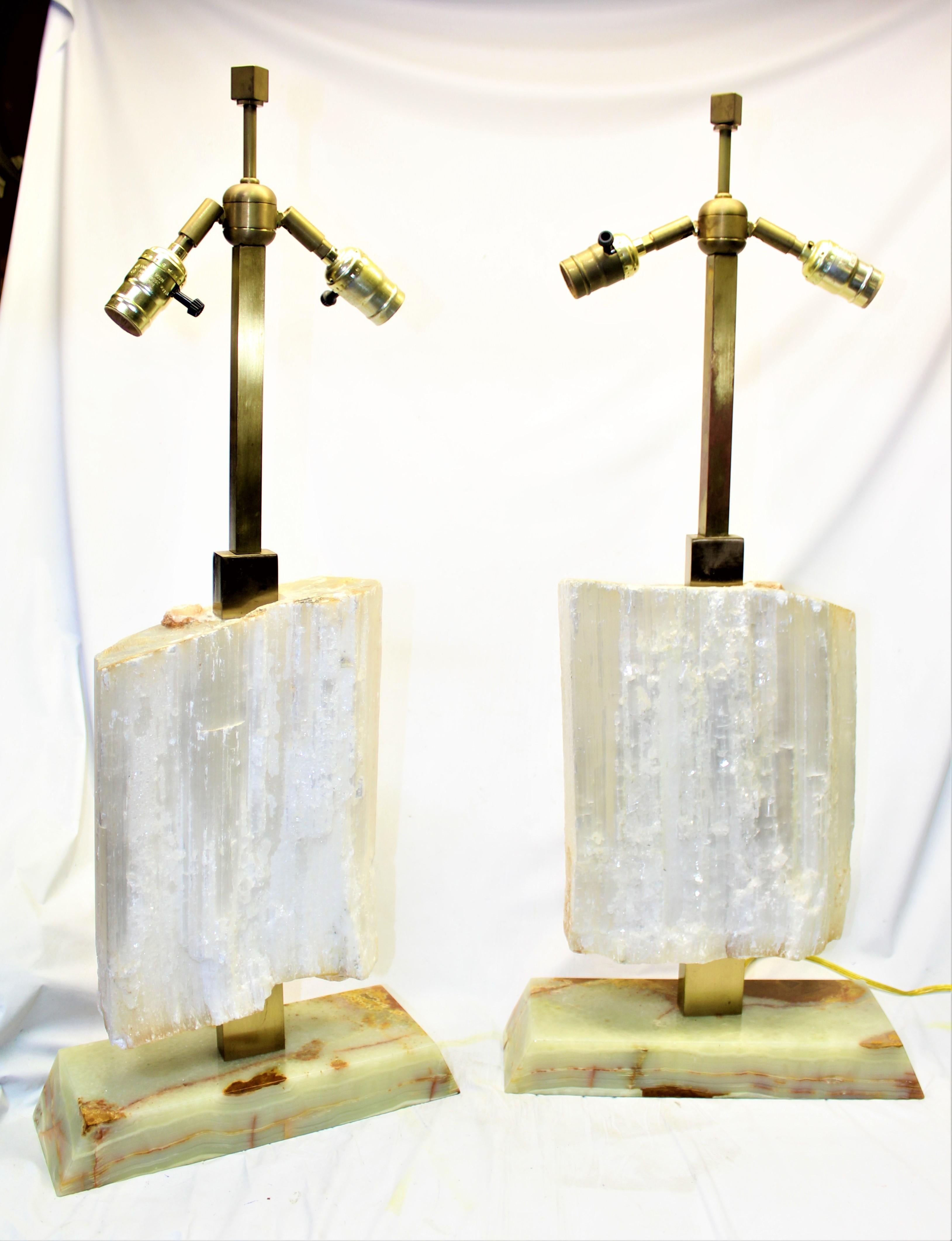 A large pair of natural selenite blocks made into lamps metal frames of solid brass hardware and with double sockets Drilled and mounted on green onyx bases. Custom made one of a kind. Will need white glove packing and shipping to protect them in