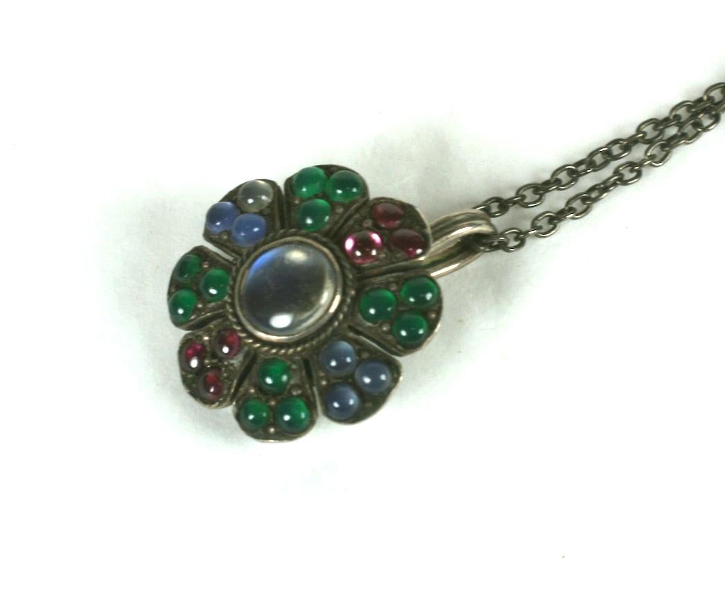 Ciondolo floriforme in pietra di luna deco con calcedonio cabochon, crio e rubino in pasta. Bella pietra di luna centrale con raffinati giochi di luce. Incastonato in argento 935, probabilmente realizzato in Germania negli anni Trenta. Una bella