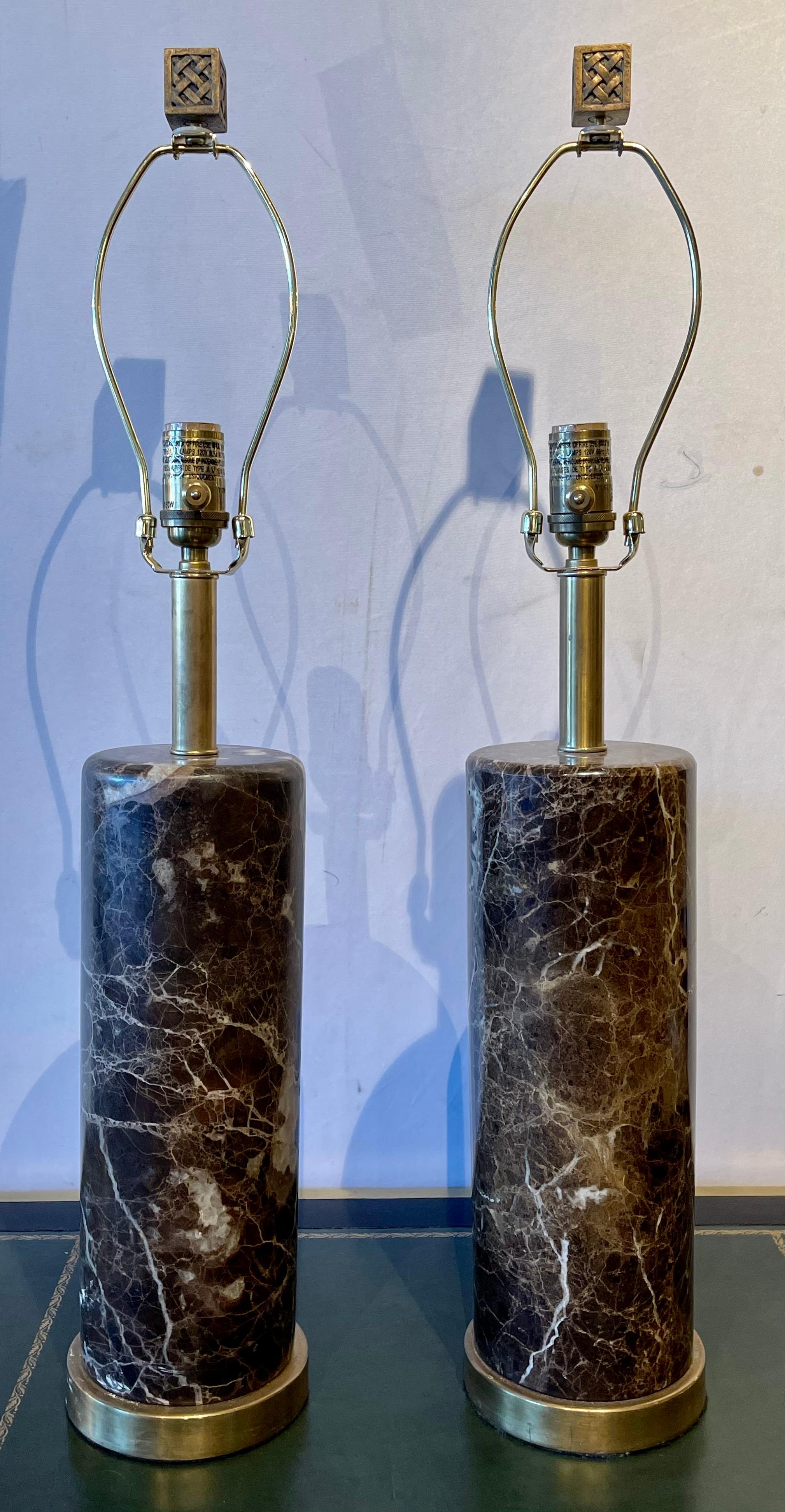 Pair of brass base marble cylindrical form table lamps with finials in the Art Deco fashion. Shades are not included.
