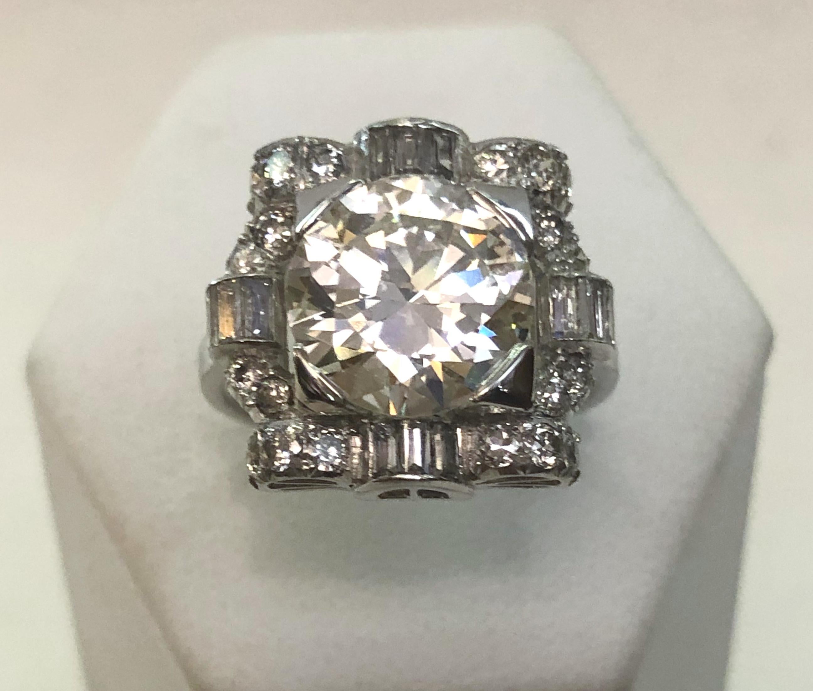 Anello italiano in platino dell'epoca art déco, con un grande diamante centrale di 3,79 carati, di colore K e purezza VS2, in taglio brillante. I diamanti circostanti hanno un taglio a baguette per un totale di 1,00 carati.
Misura dell'anello Italia