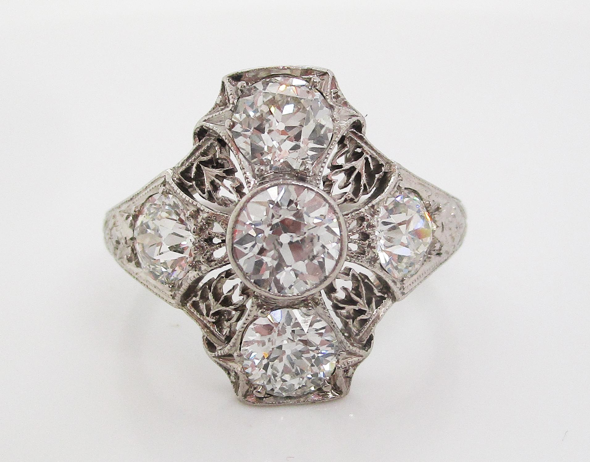 This absolutely remarkable Deco ring is in platinum with fine filigree and engraved details and boasts five breathtakingly fiery white mine cut diamonds. The unique layout of the ring features a diamond center and an almost flawlessly matched