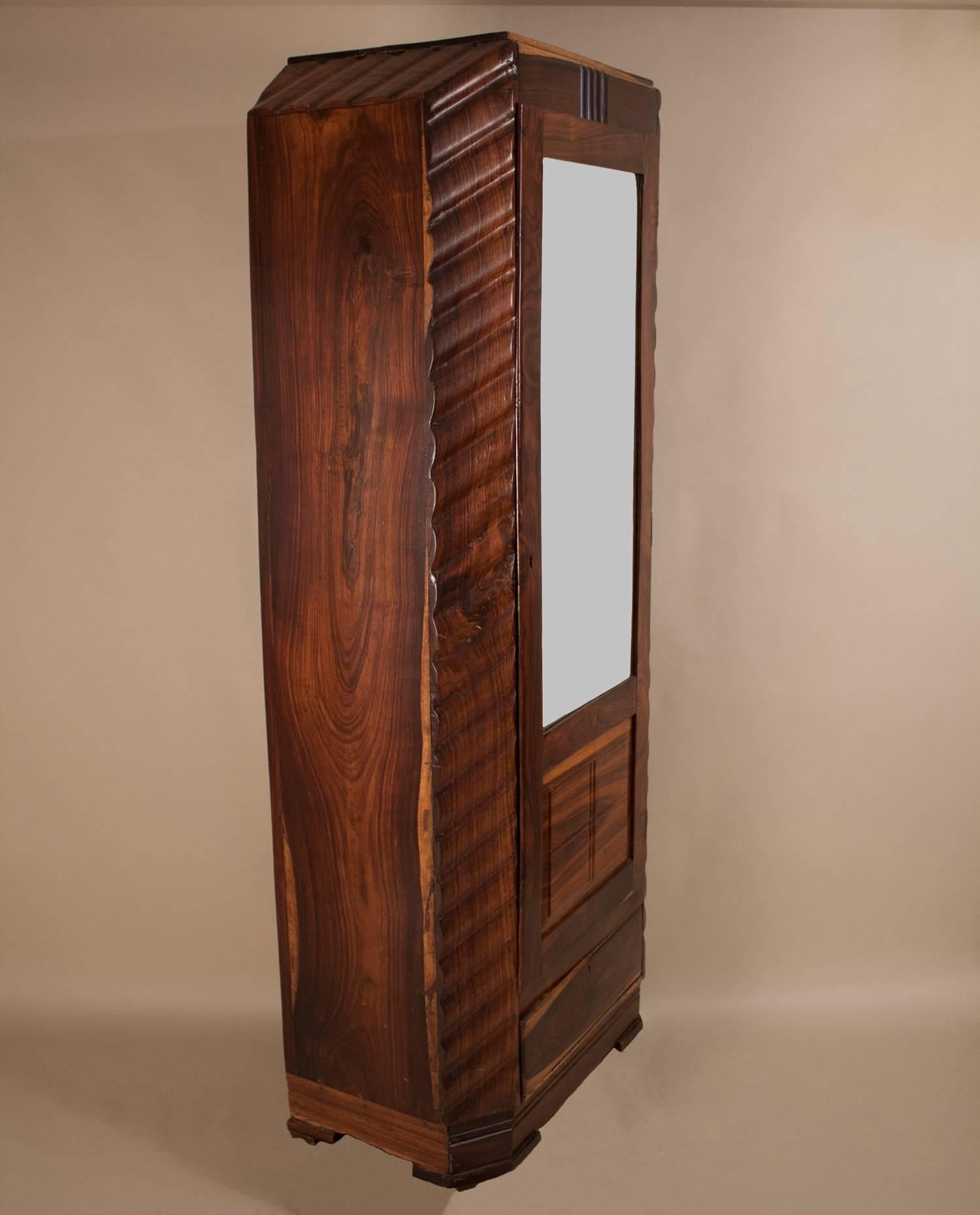 Tall, slender Art Deco wardrobe in rosewood with a rich grain and interesting tonal variations. The cabinet is carved with a consistent wave pattern and has a flattering 3/4-length mirror door with working lock and key. There are two drawers for
