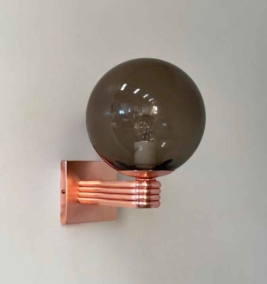 Aplique de pared italiano de estilo Art Déco con globo de cristal de Murano ahumado montado en un marco con acabado de cobre satinado, diseñado por Fabio Bergomi para Fabio Ltd, fabricado en Italia.
1 luz / tipo E12 o E14 / máx. 40W
Medidas: Alto 12