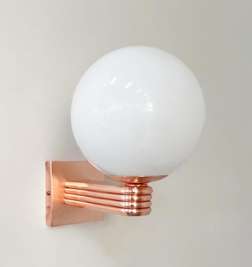 Aplique de pared italiano de estilo Art Déco con globo de cristal de Murano blanco brillante montado en un marco con acabado de cobre satinado, diseñado por Fabio Bergomi para Fabio Ltd, fabricado en Italia.
1 luz / tipo E12 o E14 / máx.