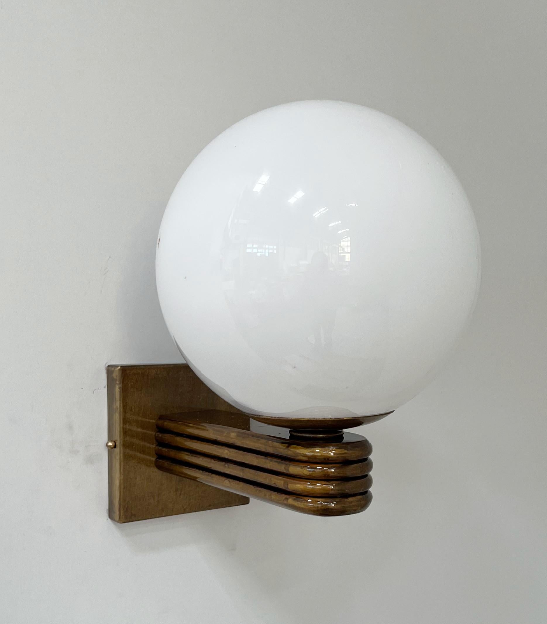 Aplique de pared italiano de estilo Art Déco con globo de cristal de Murano blanco brillante montado sobre un marco acabado en bronce, diseñado por Fabio Bergomi para Fabio Ltd, fabricado en Italia.
1 luz / tipo E12 o E14 / máx. 40W
Medidas: Alto 12