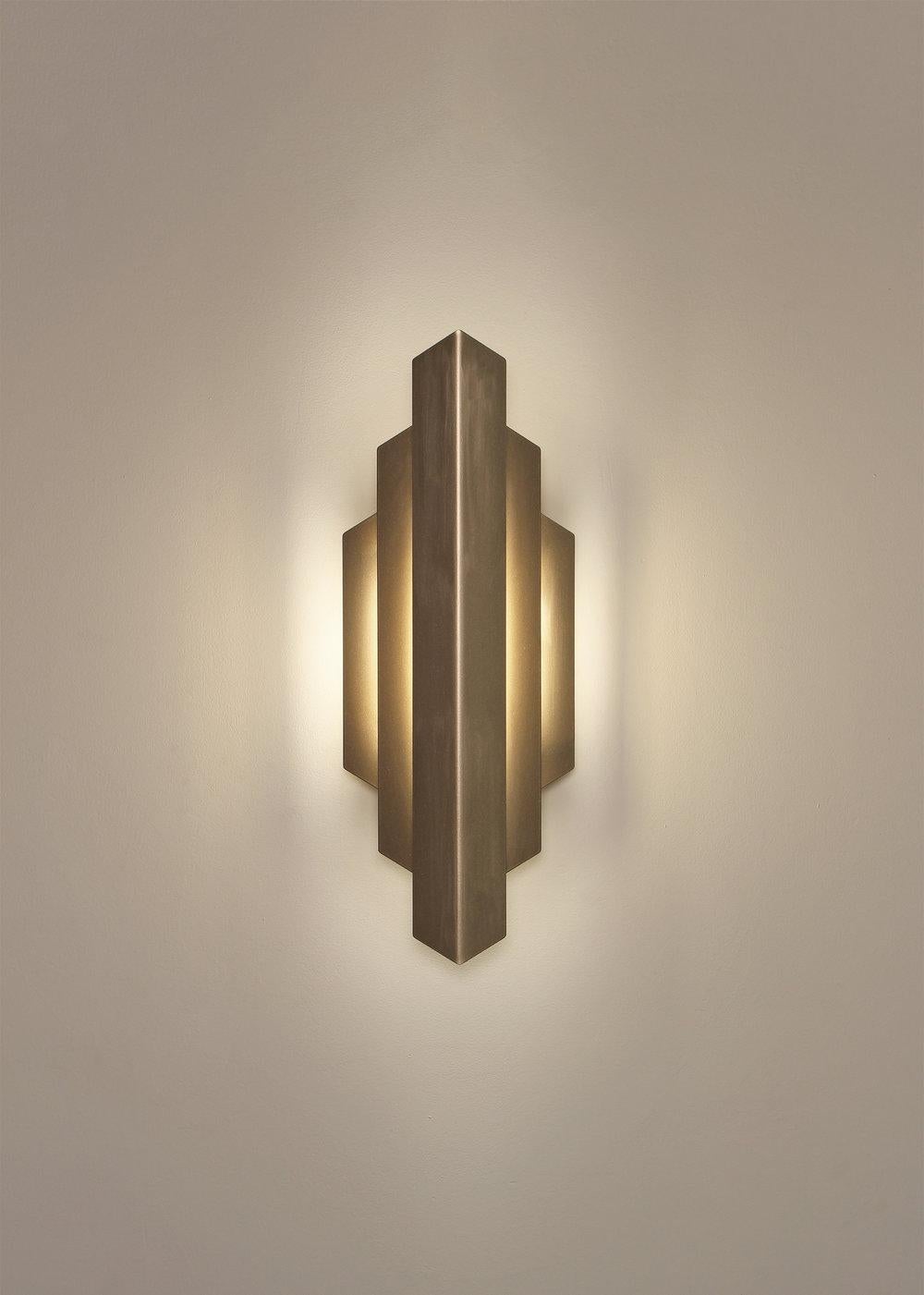 Deco sconce washes the wall with a gentle glow of indirect light. Its striking form was inspired by the bold, geometric lines that defined the Art Deco movement. Deco sconce provides a soft, accent illumination for a hallway or feature