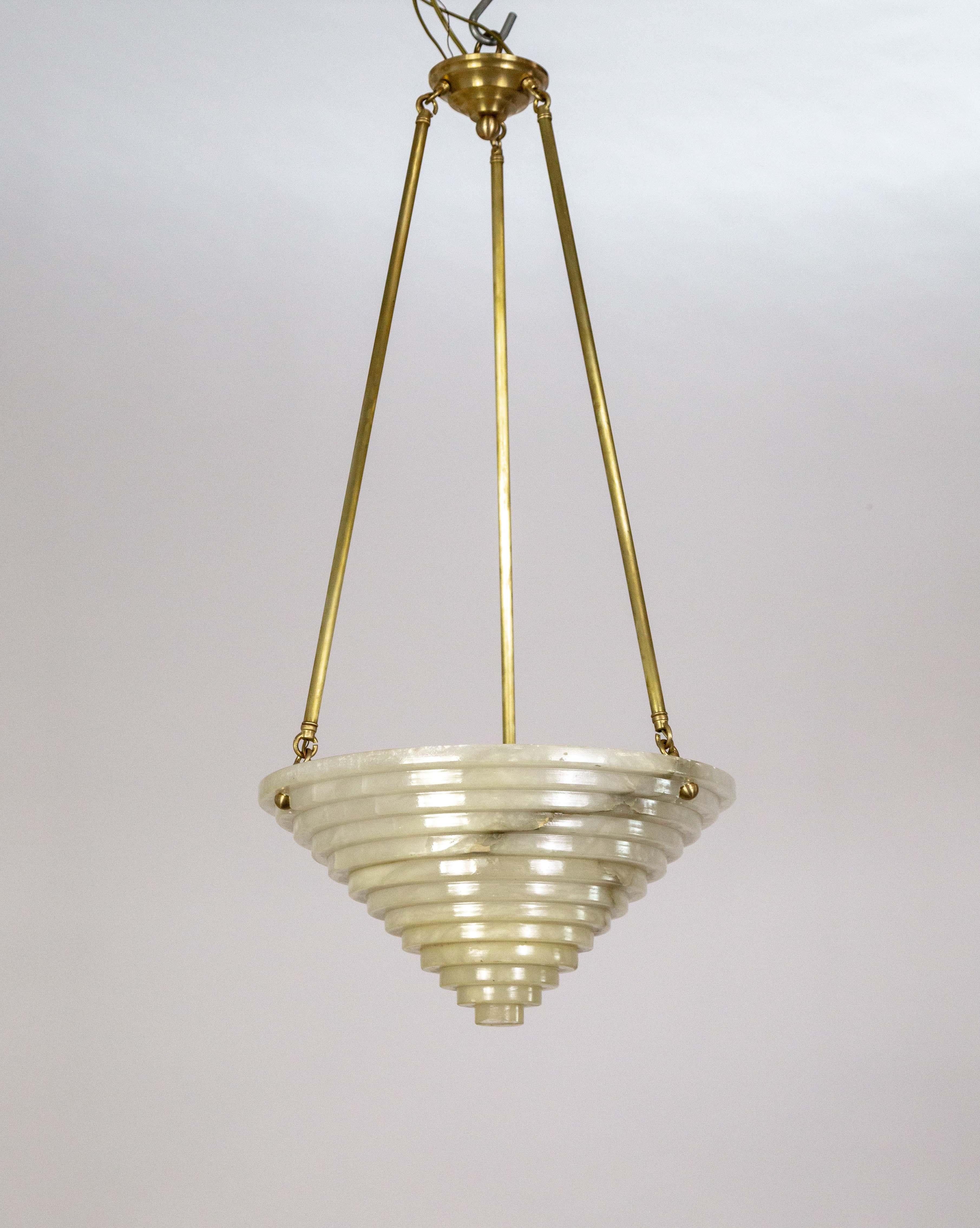 An Art Deco pendant light with an alabaster shade carved into an inverted stepped cone shape. It has three long, brass stems. The alabaster has a complex pattern of natural cracks and dark veining. Holds three medium size bulbs. 17