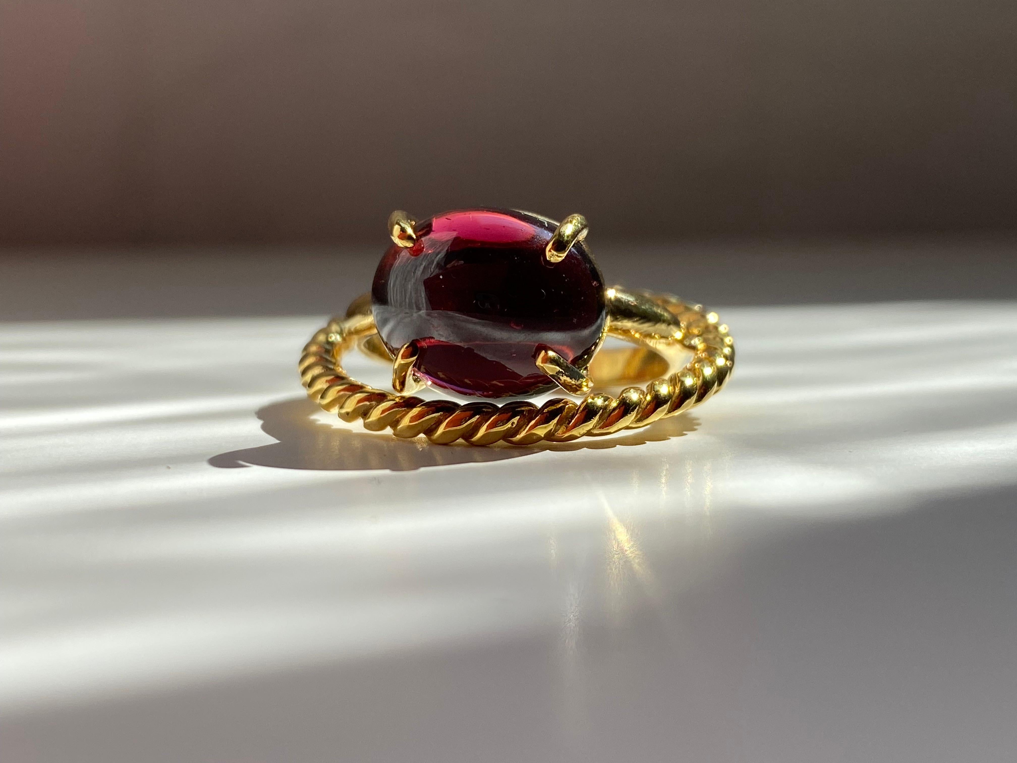 Rossella Ugolini Design Collection, Garnet ring  handcrafted with two strips intertwined together in 18 karats Yellow Gold. A Modern style design ring with an oval cabochon Garnet.
Inspired by the union of two loves that twist together in a single