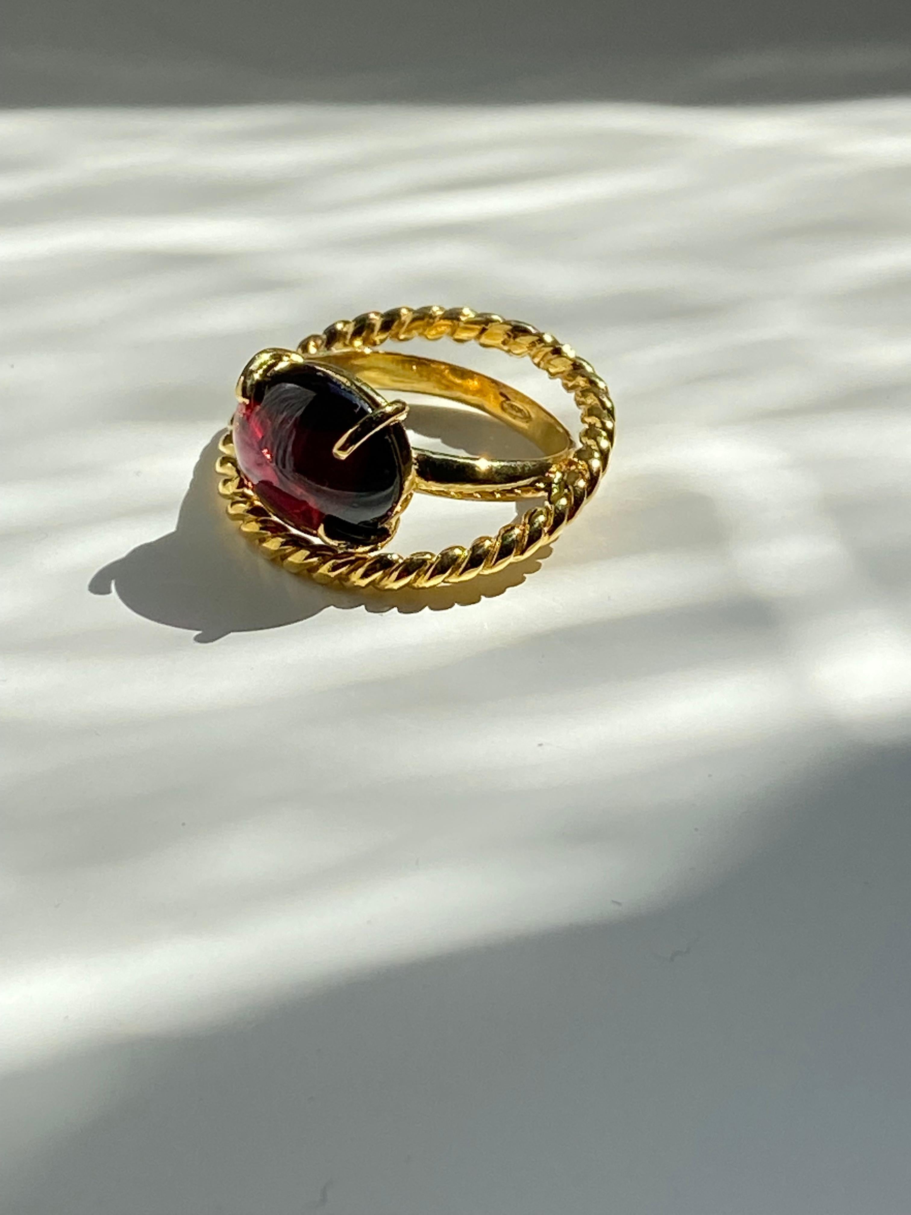 Rossella Ugolini design collection, a  ring made of two crossed gold threads touching each other creating a beautiful unique ring. A modern style design ring with an oval cabochon garnet. Inspired by the union of two loves that twist together in a