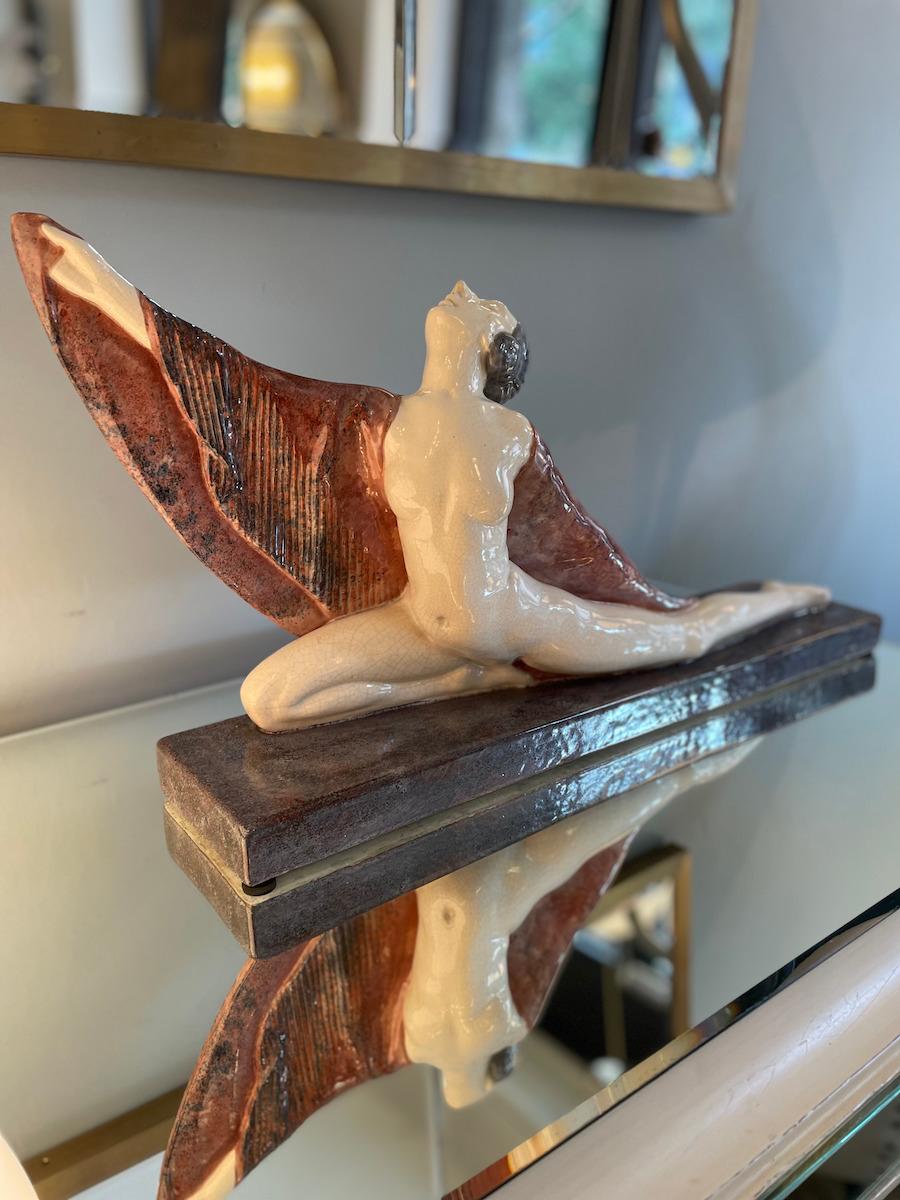 Scultura raffigurante una ballerina degli anni '40. La ballerina poggia su una base smaltata bordeaux, con il corpo bianco, e il suo movimento è esaltato da un mantello colorato il cui drappeggio aggiunge un tocco raffinato e sofisticato al pezzo.