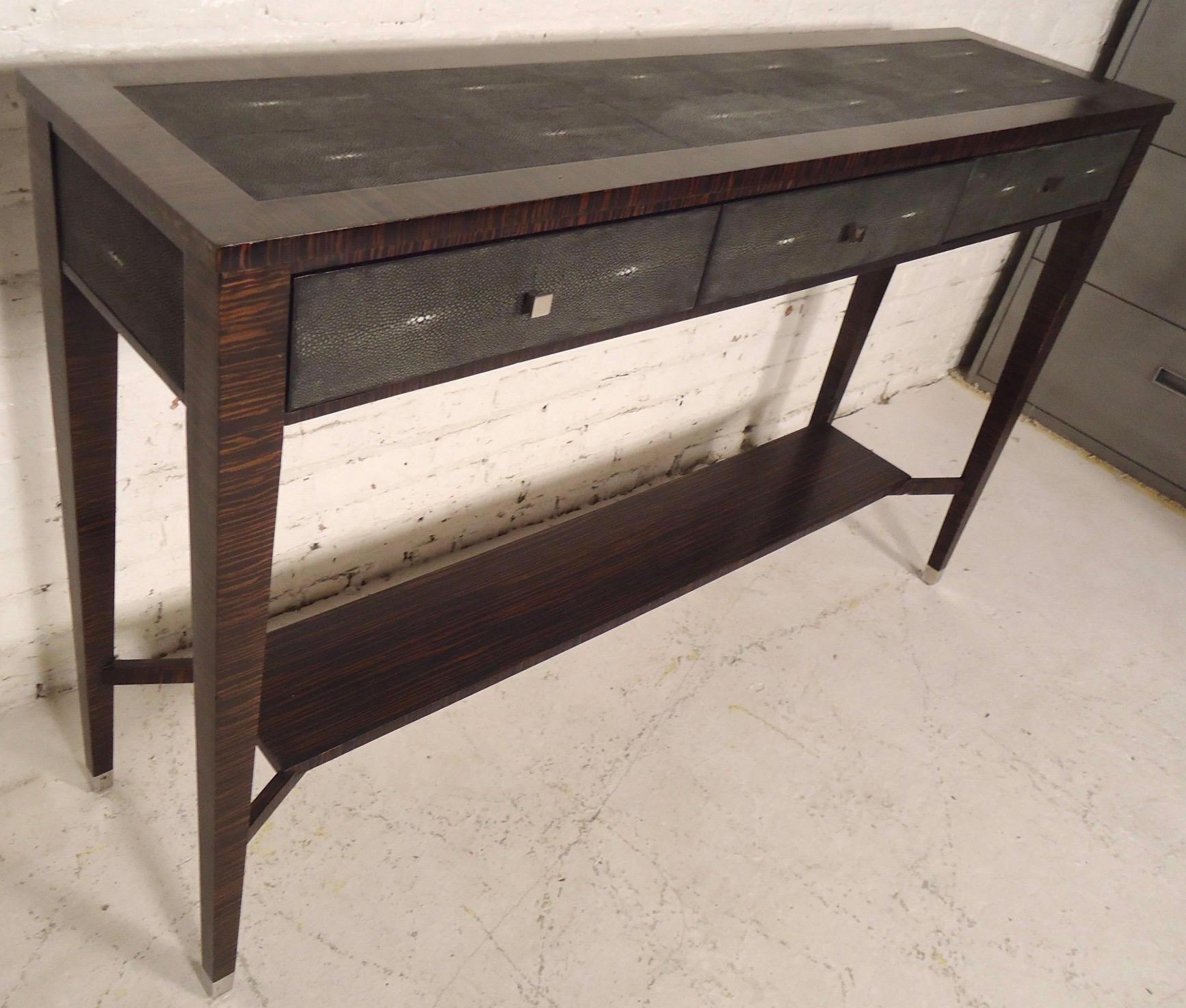 Longue table console avec placage en faux ébène de Macassar et accents en faux galuchat. Trois tiroirs avec poignées en nickel, pieds fuselés avec capuchons en nickel assortis. Très belles couleurs et design.

(Veuillez confirmer l'emplacement de
