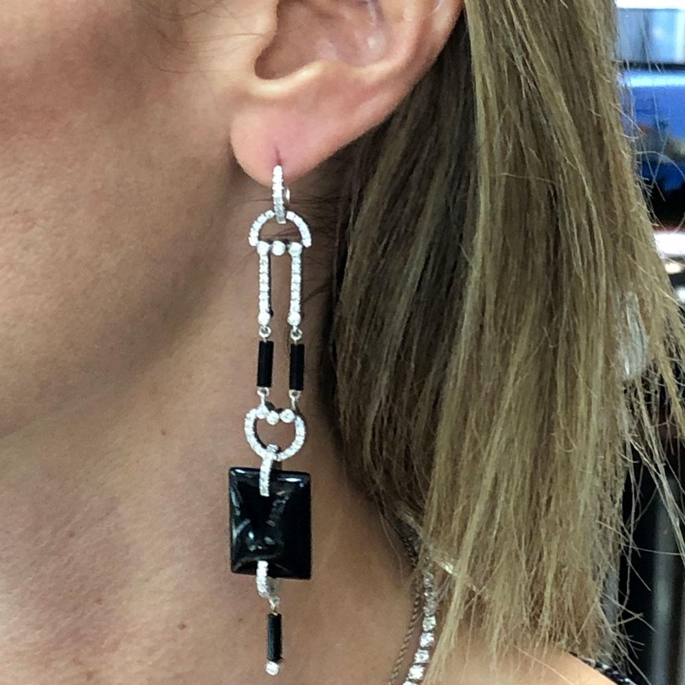 These fabulous dangle earrings feature round brilliant cut diamonds and geometric shape onyx and are fashioned in 18 karat white gold. There are approximately 1.50 carat total weight of diamonds graded G-I color and SI1 clarity. The earrings measure