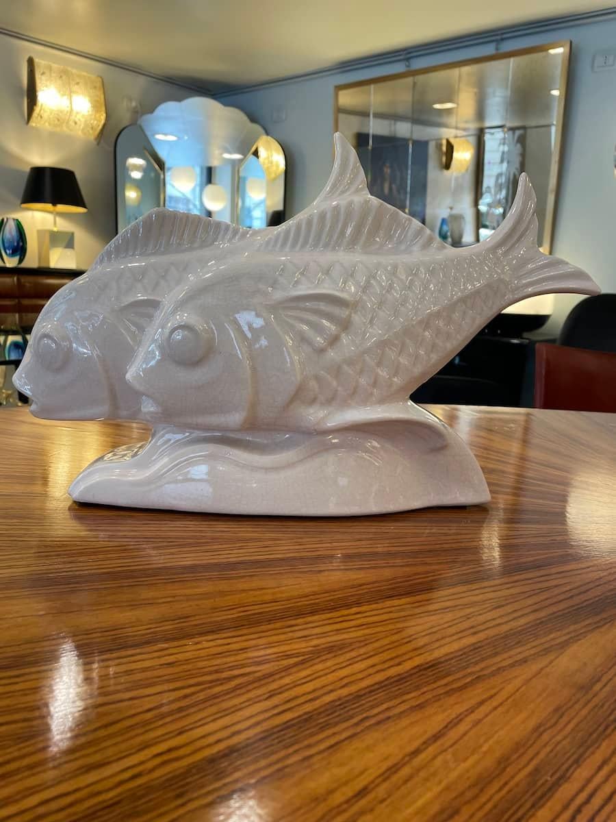 Sculpture of two white ceramic fish from the 1940s.
The fish feature the key characteristics of the Art Deco movement, highlighted by their soft lines and dynamic shapes. The special craquelé finish adds a refined and sophisticated touch to the