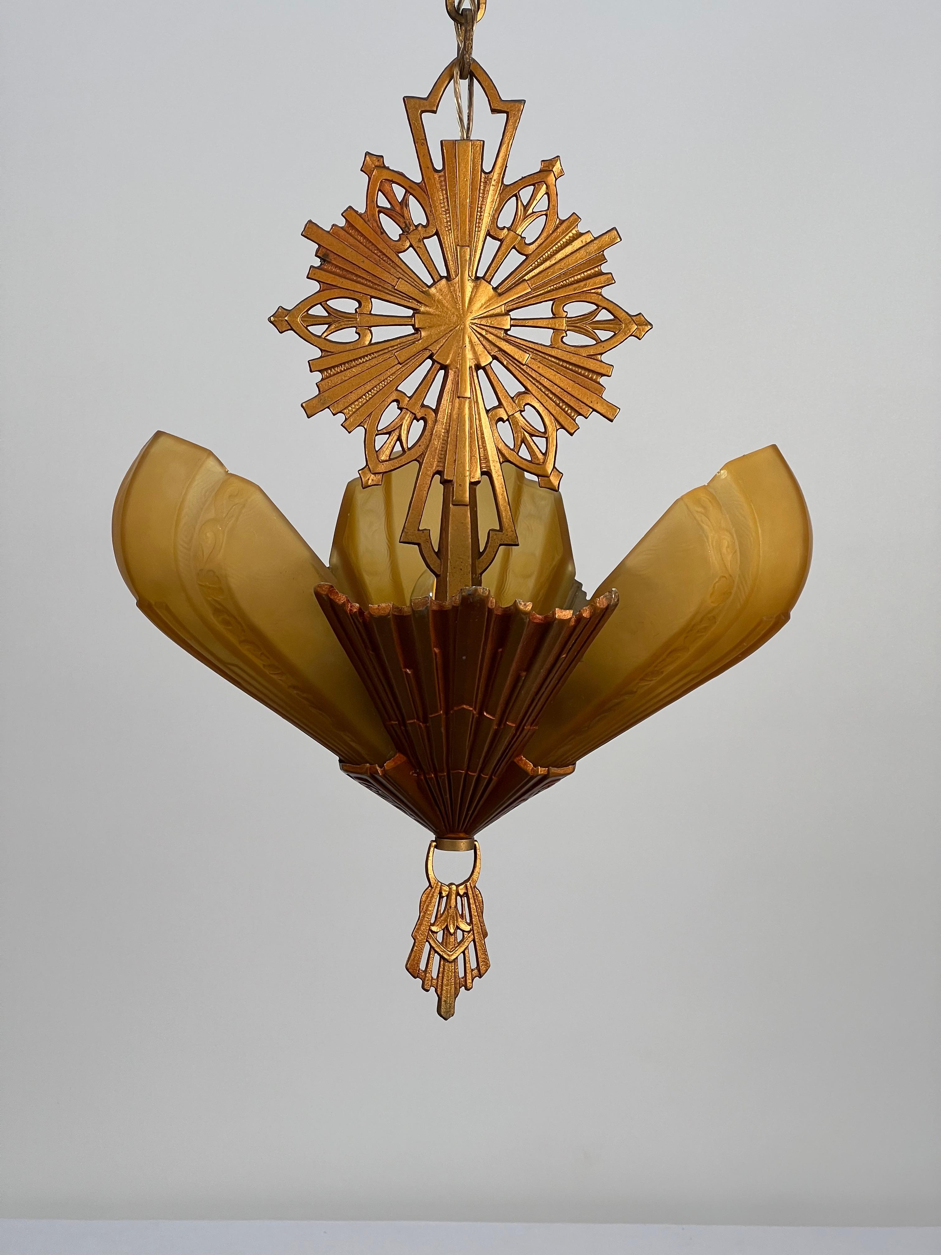 A spectacular art deco three light fixture featuring beautifully detailed amber glass slip shades. The wave texture present on the inside of the glass projects to the outside as a subtle texture. The glass shades are bordered with embossing's of