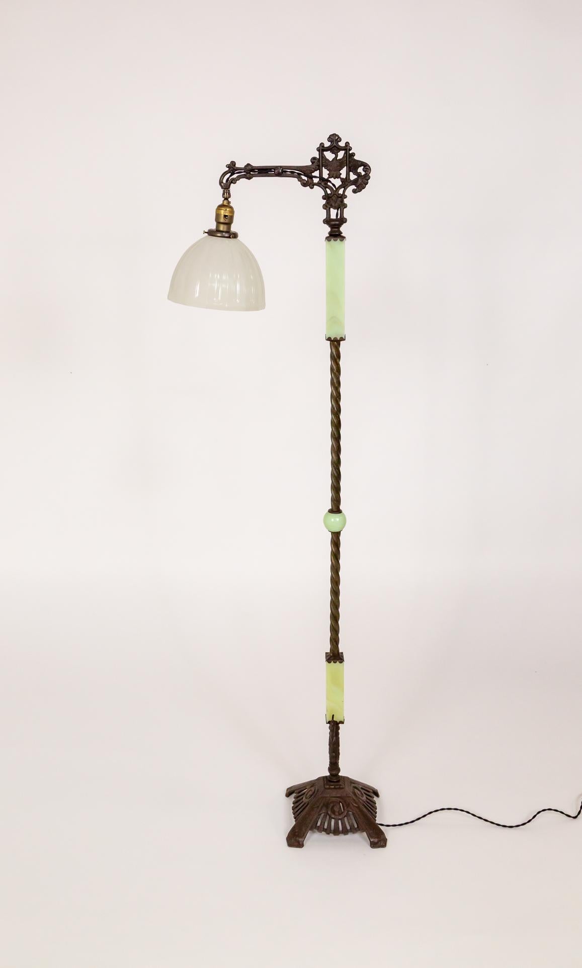Lampada da terra a ponte dei primi del Novecento in ghisa decorata e vetro giallo-verde uranio. La parte superiore presenta un intricato disegno di uccelli, il gambo è lavorato in forma contorta con segmenti rettangolari di vetro all'uranio. La base