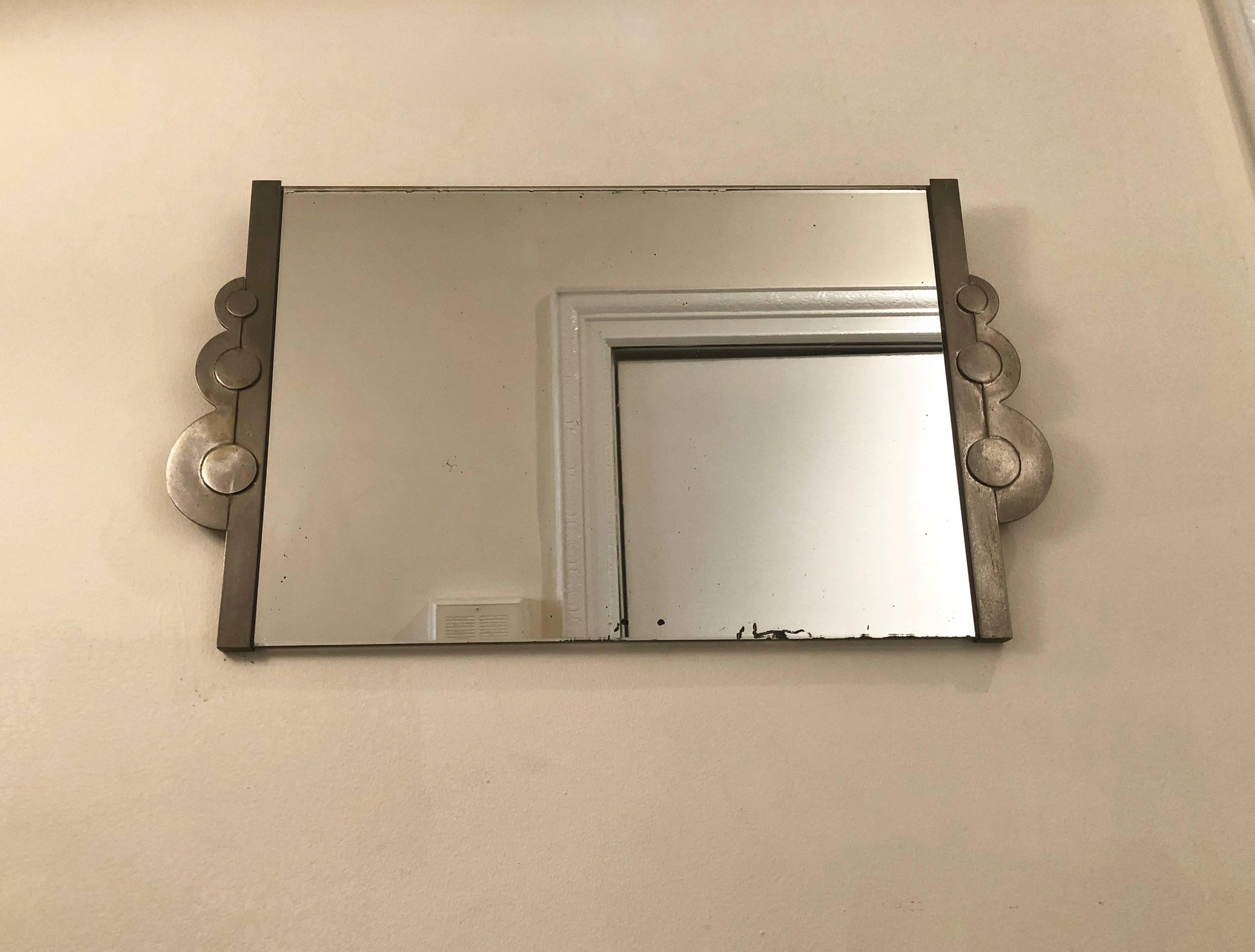 Rectangular American Deco wall mirror has a steel frame retaining its original patina and signs of original brass plating detail and slight aging marks on mirror.