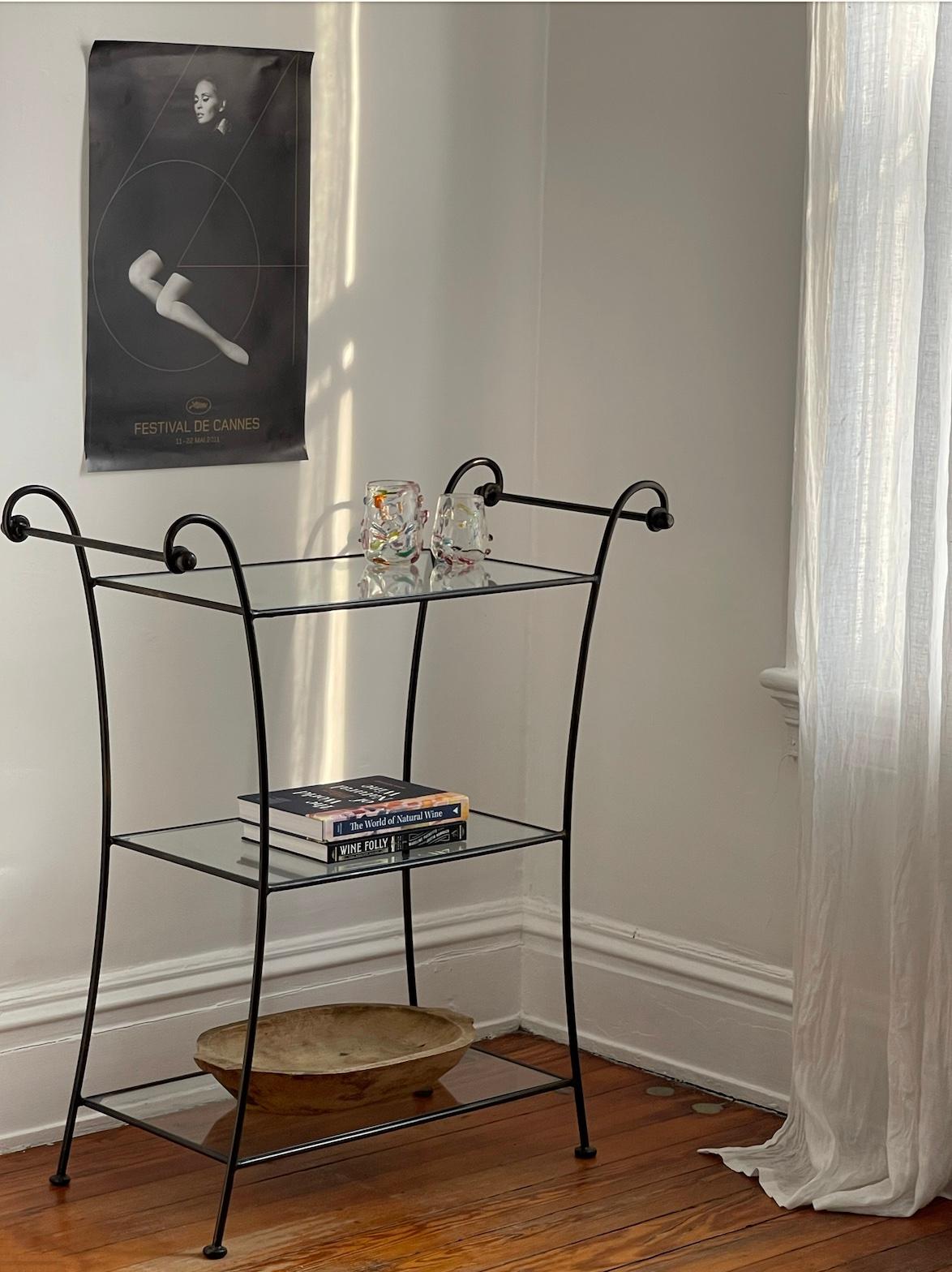 Elegant bar cart in the art deco style with wrought iron frame and three glass tiers. Perfect for serving drinks at Apéro hour. A versatile, timeless piece.