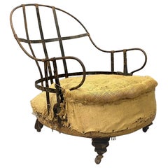 Fauteuil ancien déconstruit à structure en bois et fer exposé avec haut dossier incurvé