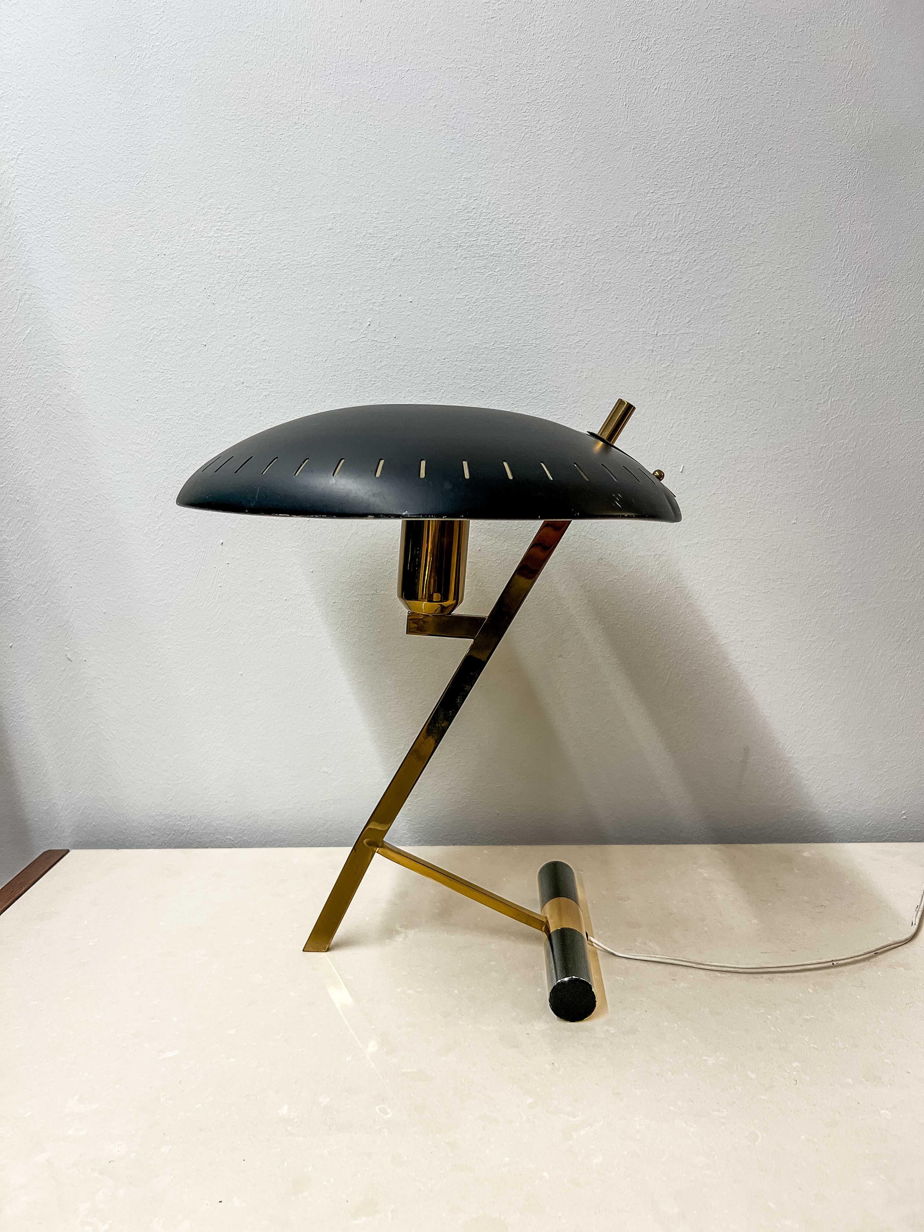 The “Decora” desk lamp, designed by Louis Kalff for Philips, is a true testament to the mid-century modern design movement. With its distinctive UFO-shaped shade and elegant, angular brass stand, this lamp exemplifies the sleek functionality and