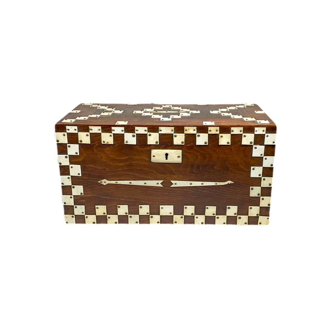Stained pine with hinged top, decorated with geometric design out of recycled piano keys. The interior with a removable organizing drawer. Illegible names with numbers are faintly written in pencil on the inside lid, American, circa 1920-1940.