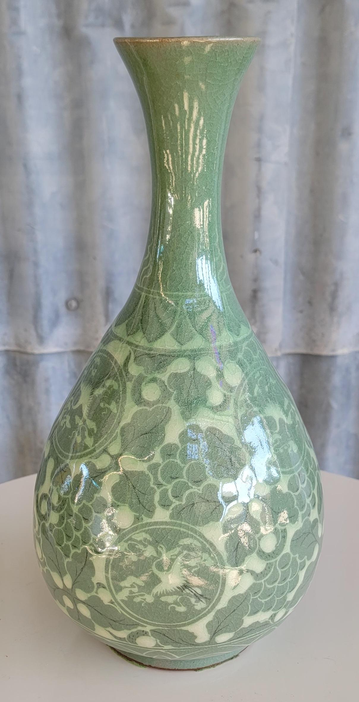 Beautifully decorated porcelain Celadon vase. Decoration appears to be grape vines with medallions of the Phoenix bird. Measures 12.13 inches tall. Faint, undecipherable signature on base. I believe this to be from the mid to late 20th century and
