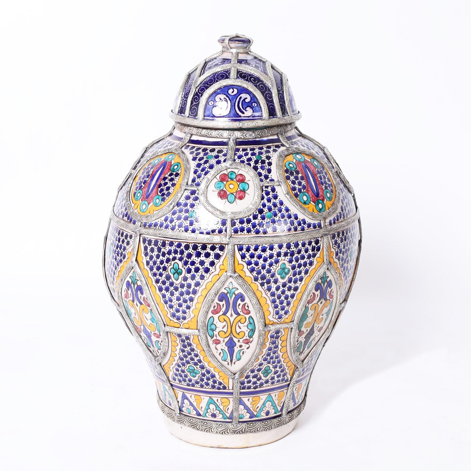 Large glazed terra cotta urn decorated with floral and geometric designs in traditional mediterranean colors featuring applied jewelry style high quality metalwork.