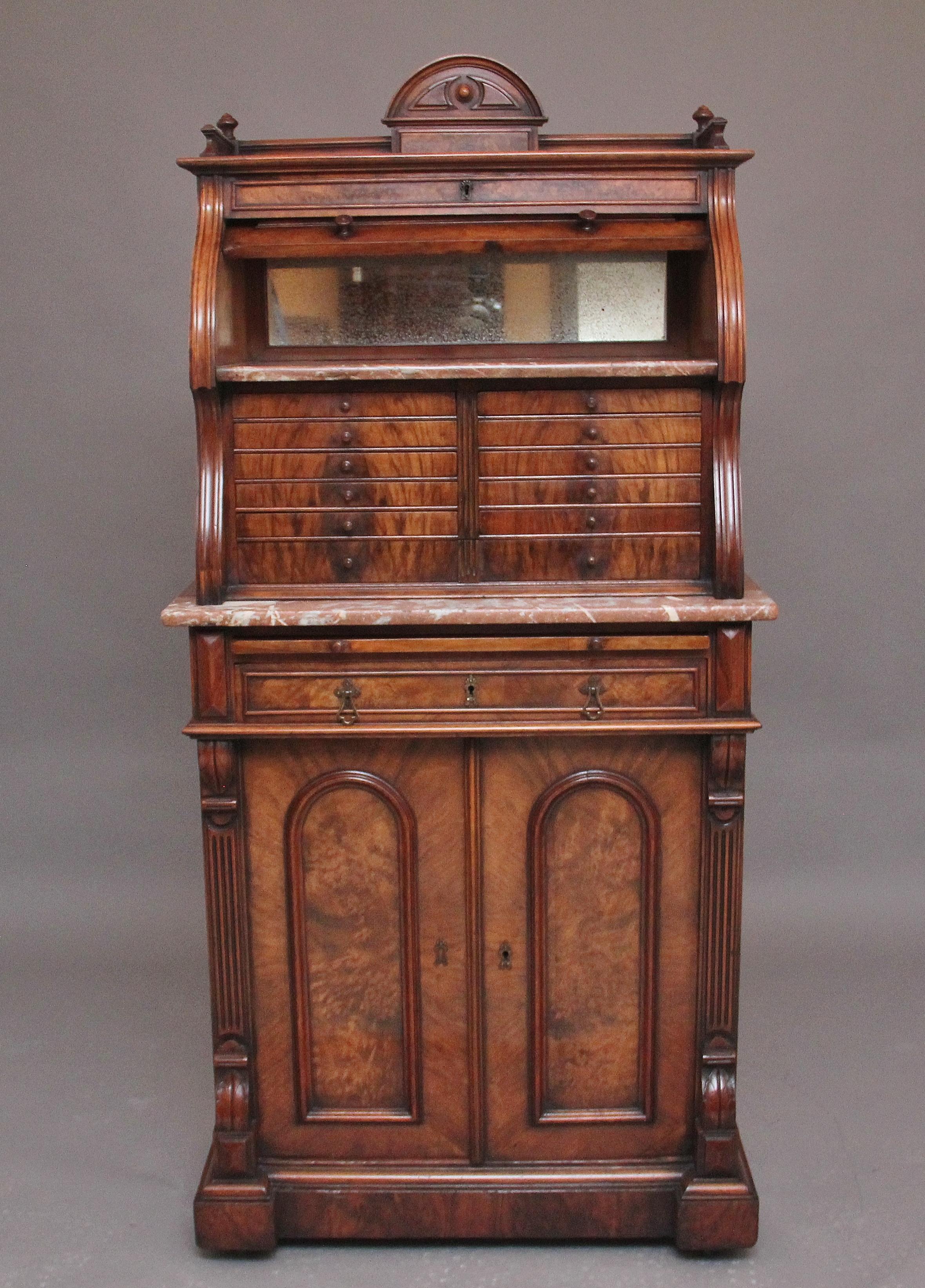 19th Century Burr walnut dentist cabinet, the top section having shaped gallery with turned finials either side and decorative moulded carving at the centre, the panelled cylinder opening to reveal a mirror and pink and white marble, twelve burr