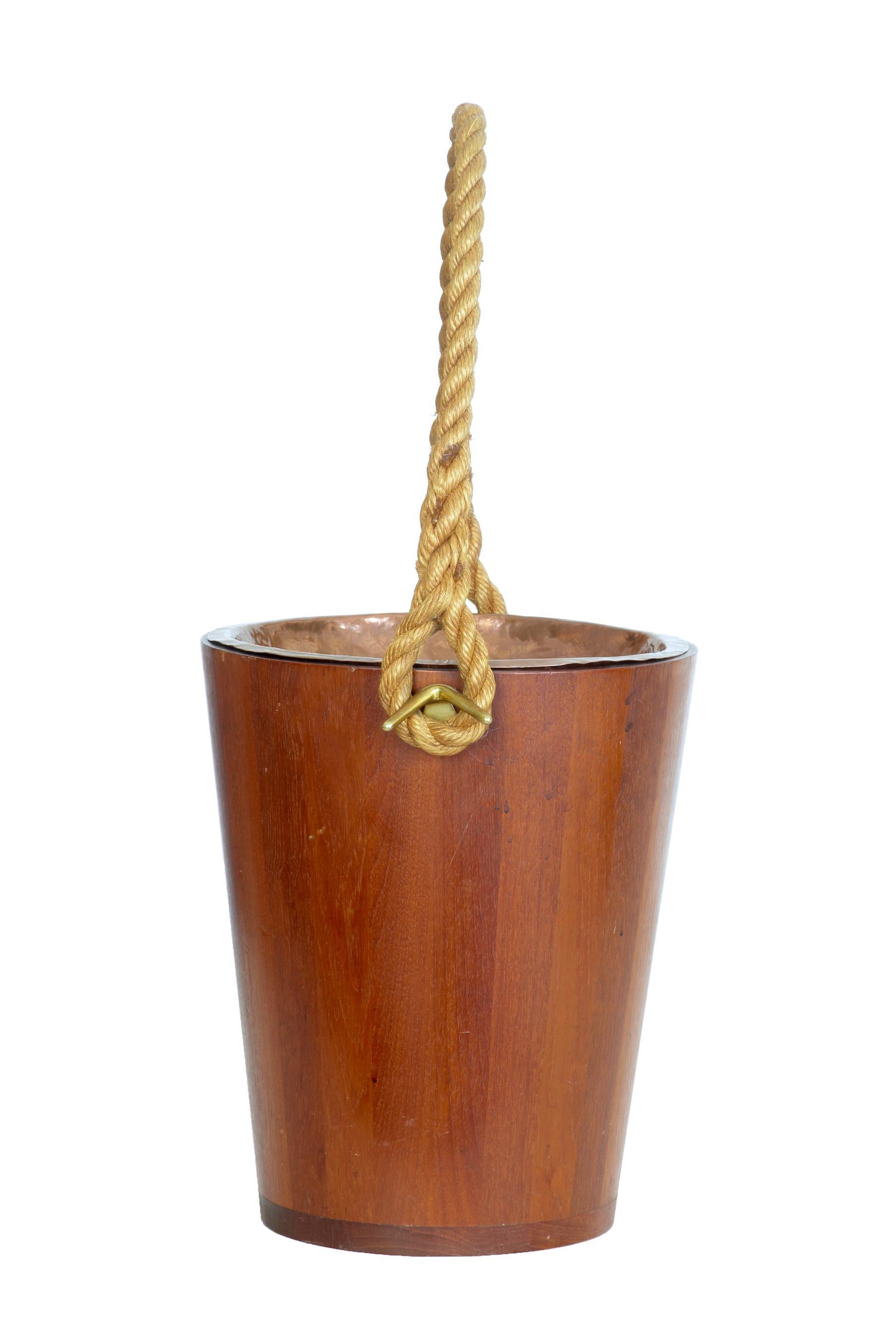 Decorative 20th century teak bucket with rope handle, circa 1950.

Ideal for use as a waste paper basket or a kindling bin beside the fire. Teak bucket with removable copper dish.

Minor surface marks.