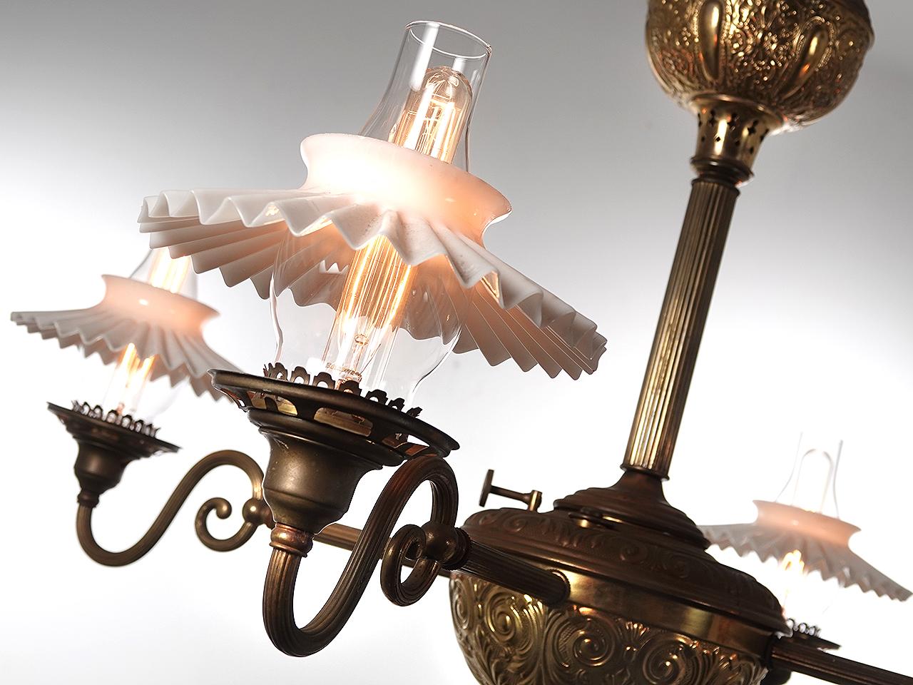 This is a large fuel lamp showing 2 decorative tanks. The four arms are 41 inches across. I like 4 arm lamps because they have a cleaner older look and are less fussy. This example uses 4 ruffled milk glass shades over a clear chimney. We newly