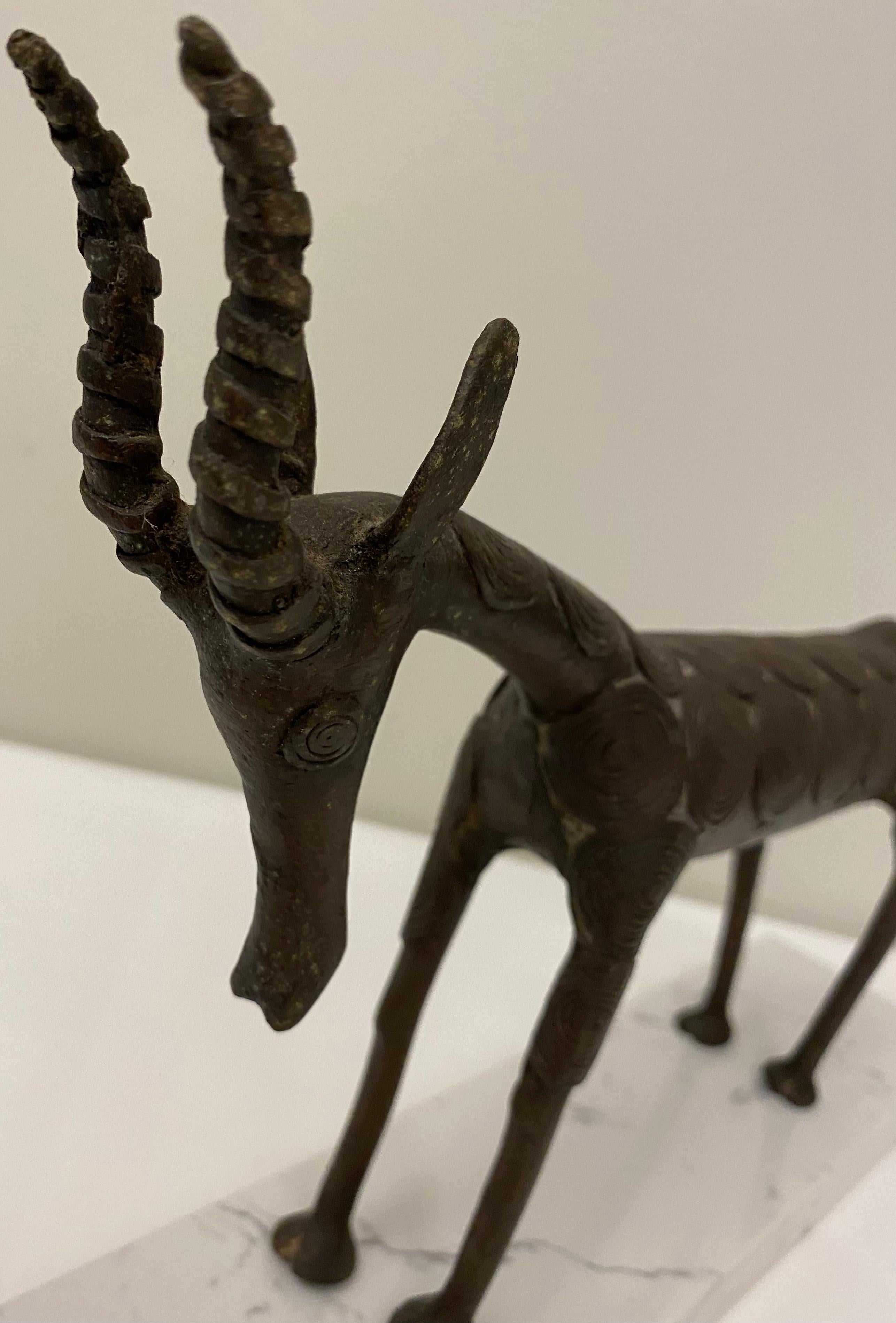 Intricately hand-crafted African antelope, Benin tribal sculpture.
Details in hand-hammered bronze on wood small pieces attached with small nails and numerous carvings. 

This object form is one of the best-known examples of Benin art, created