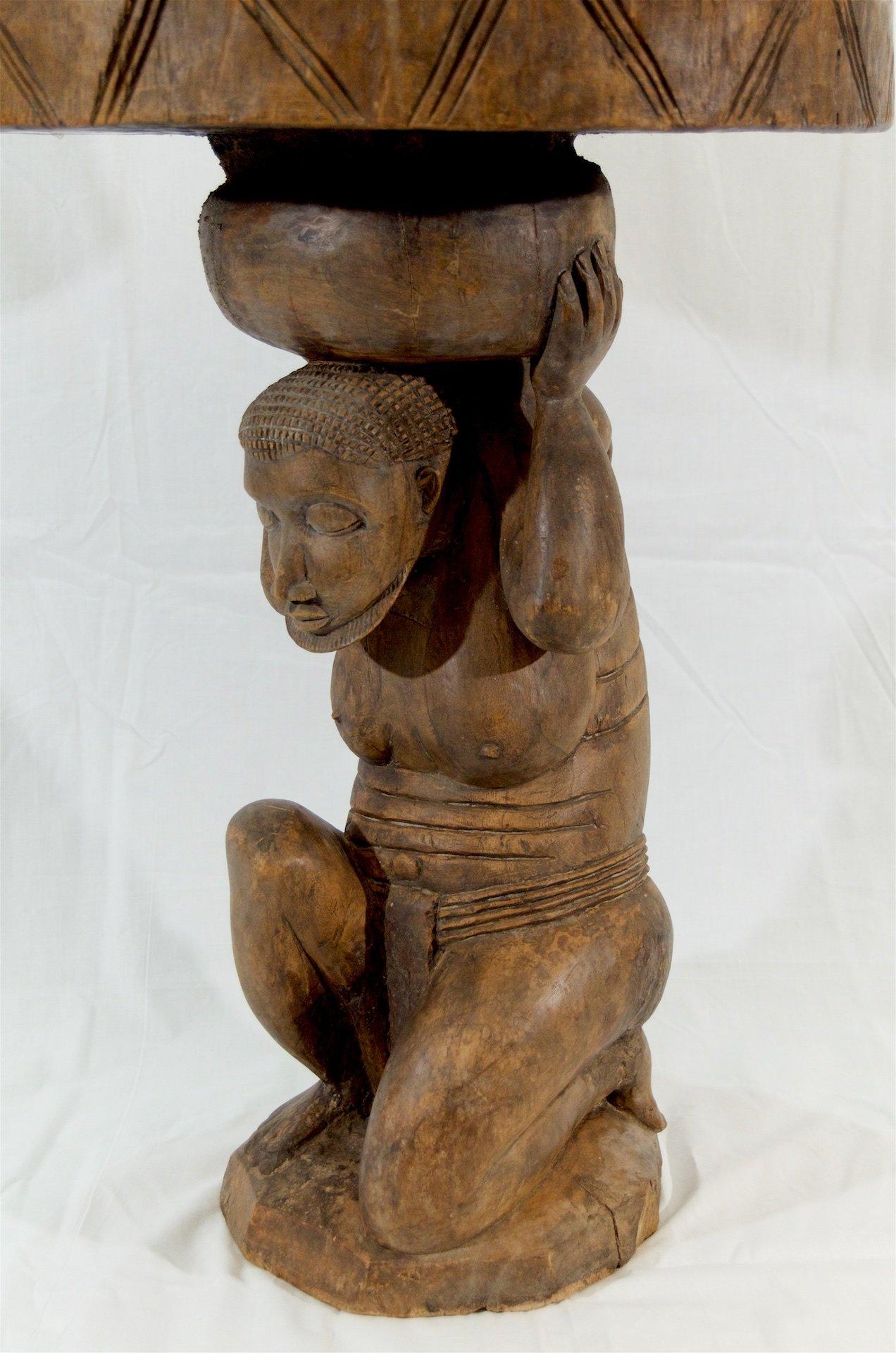 A unique side table carved of a crouching figure from a single piece of wood.