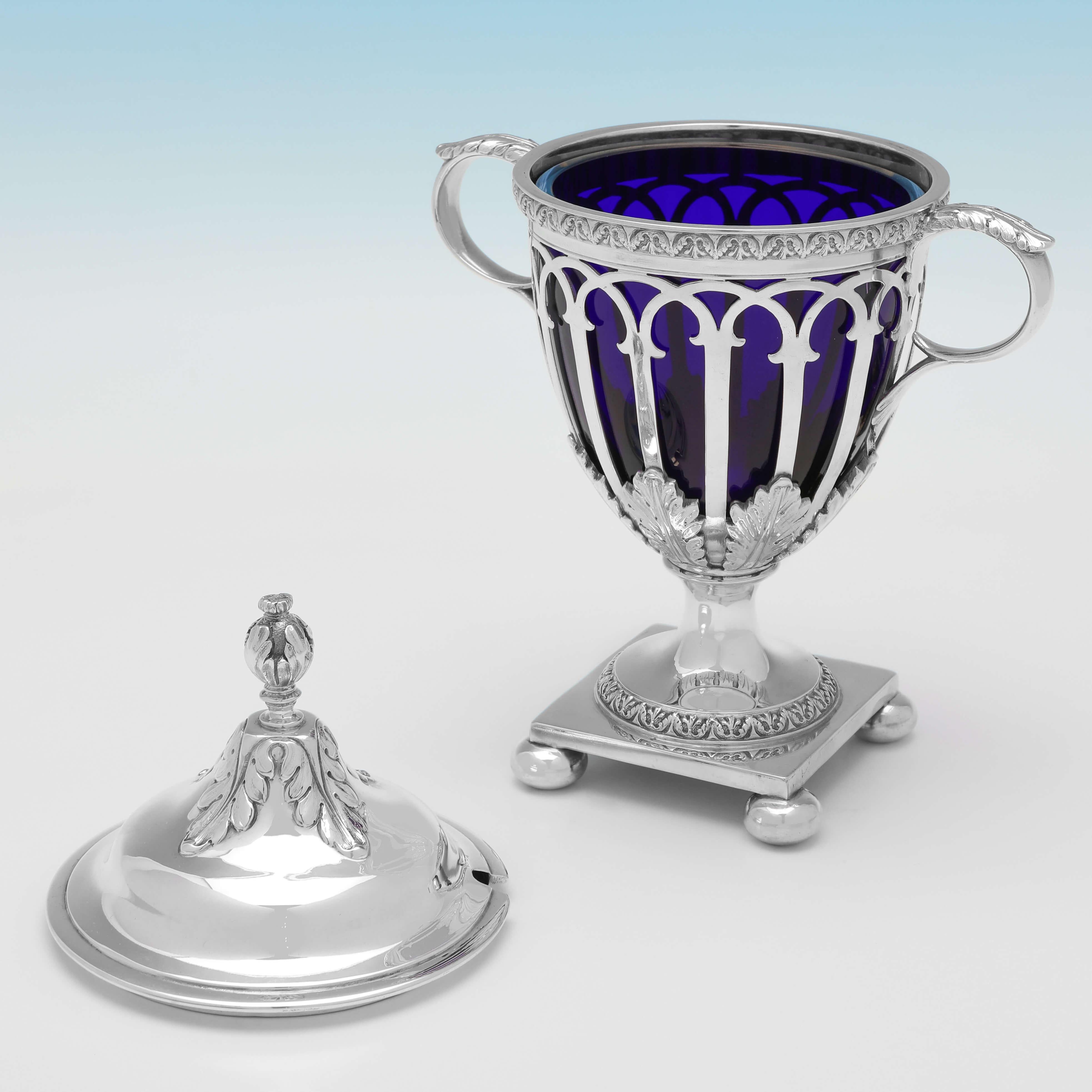 Hallmarked in London in 1912 by George Howson, this attractive, antique sterling silver sugar basket, is in the Neoclassical revival taste, and features a blue glass liner and removable lid. 

The sugar basket would also work well to serve other