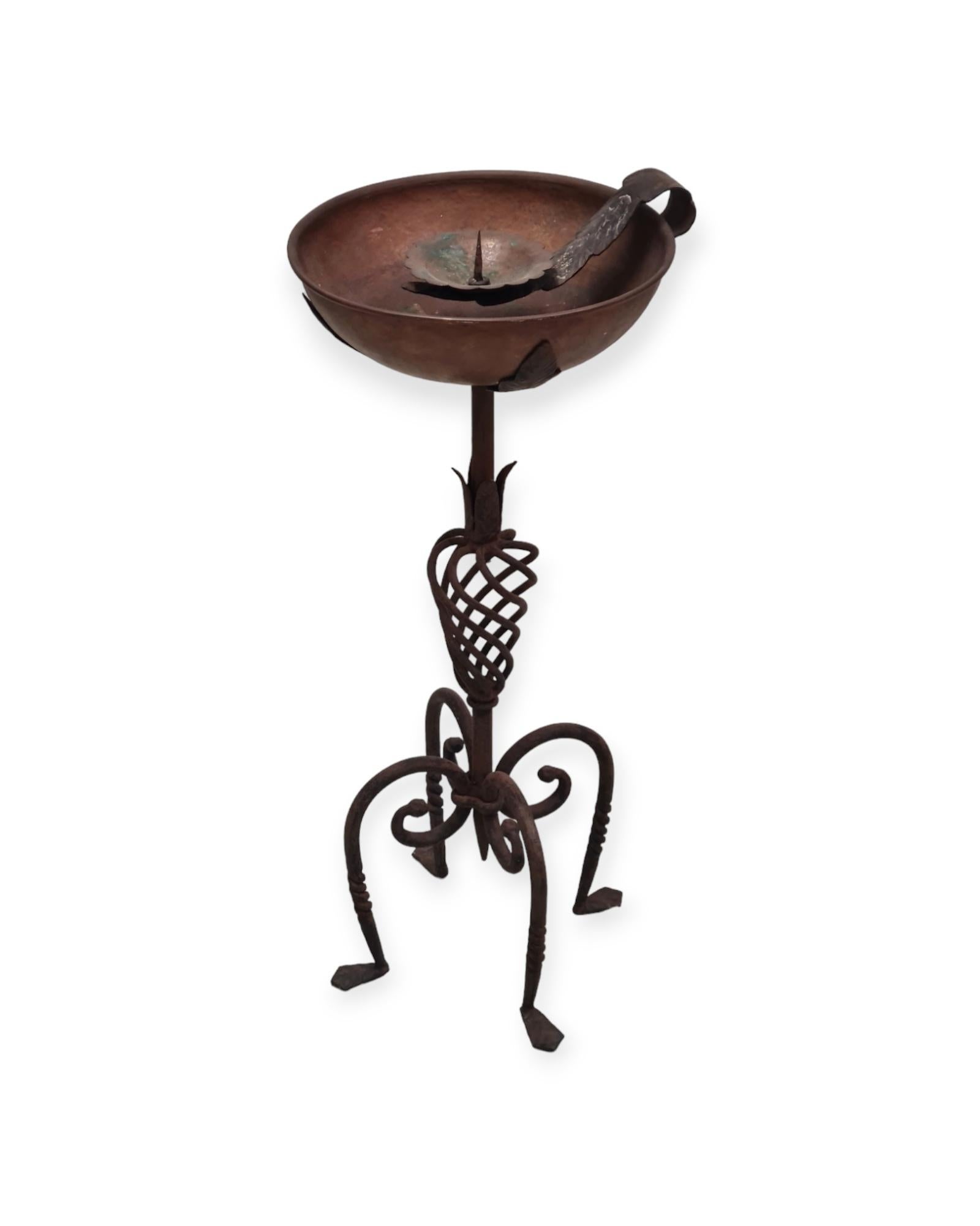 A beautiful torchére piece by the leading metal and wrought iron master Antti Hakkarainen made through his metal workshop Taidetakomo A. Hakkarainen. 
This candle holder is very rare and combines an iron decorative stand with a copper dish to