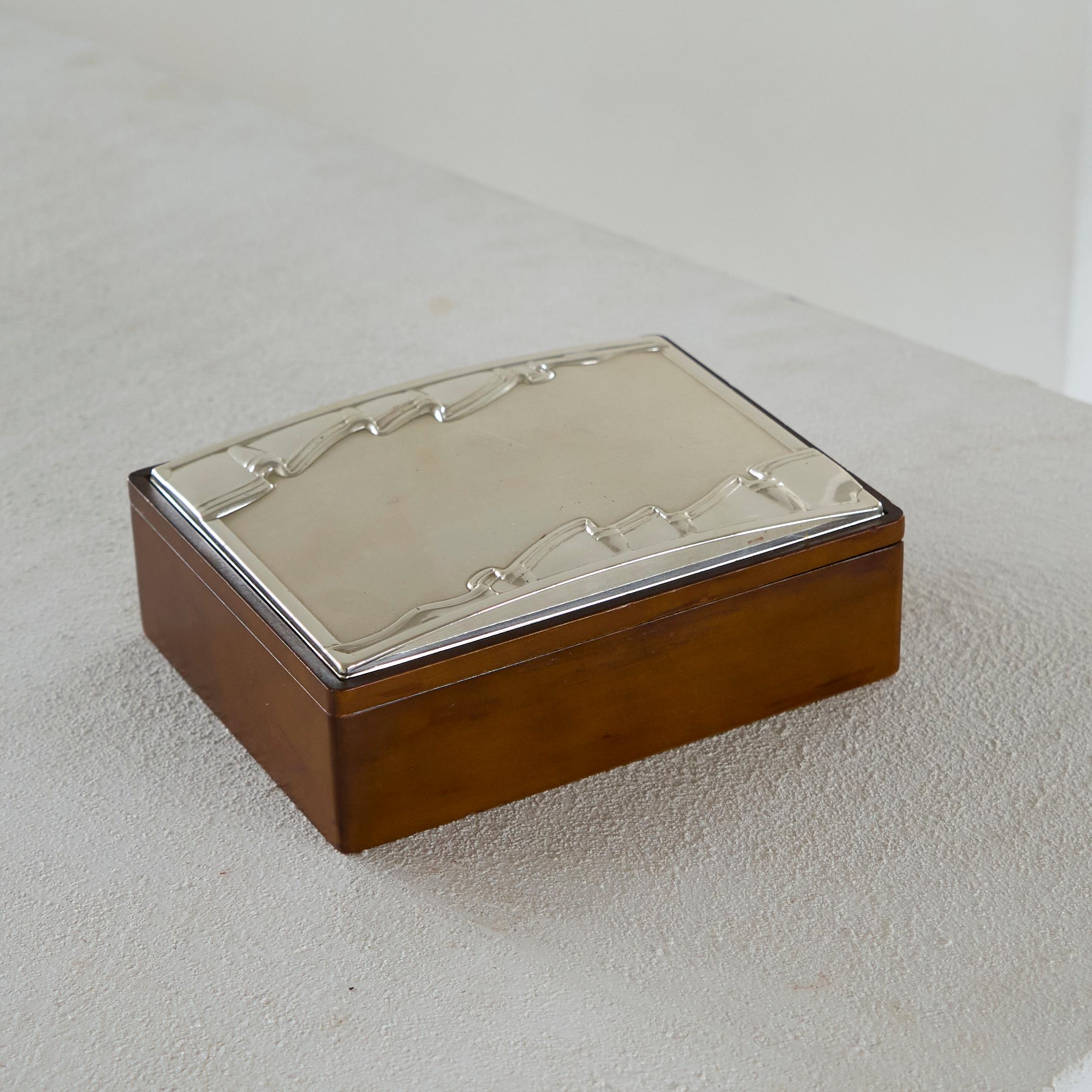 Decorative Art Deco Style Lidded Box in Wood and Silver 1970s.

A very interesting and beautiful lidded box with an art deco inspired lid in silver. Great abstract and timeless design. High quality execution, could well be used as a decorative box